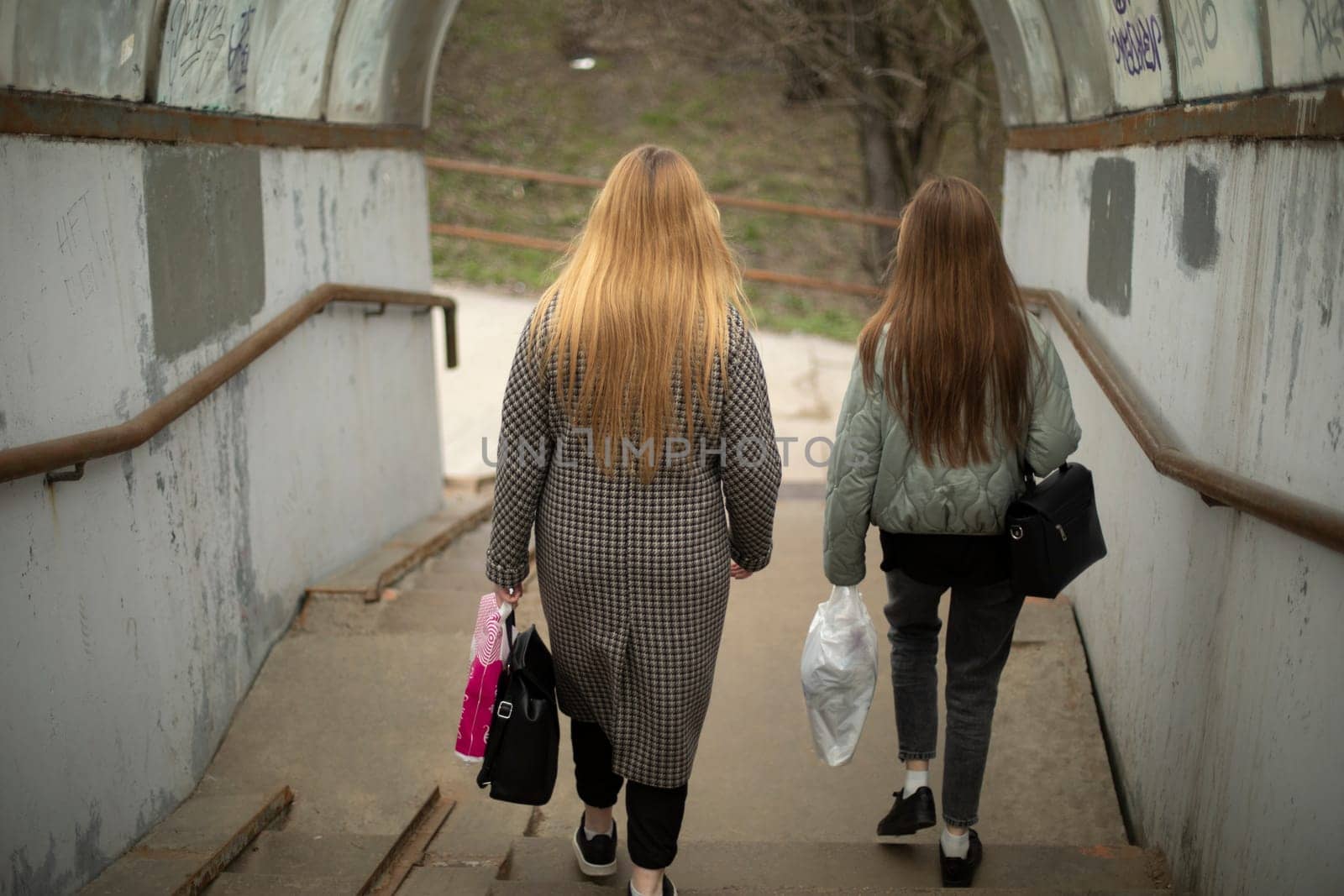 Girls walk up stairs. Girls with bags. Descent through tunnel. Pedestrian crossing for people.