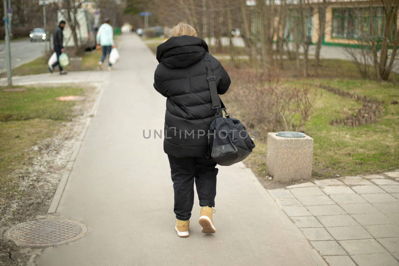 Woman in black clothes walks down street. Woman in town. Walk through city area.