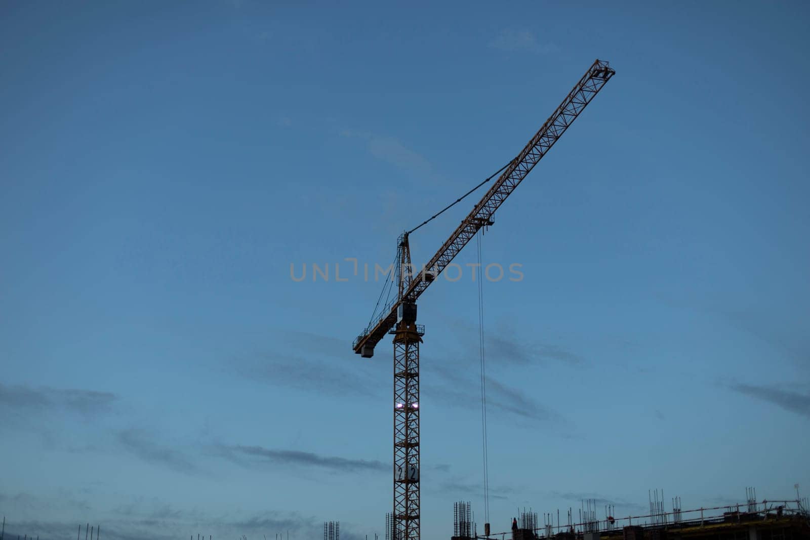 Tower crane at construction of building. High-rise crane for lifting plates. Heavy machinery at construction site.