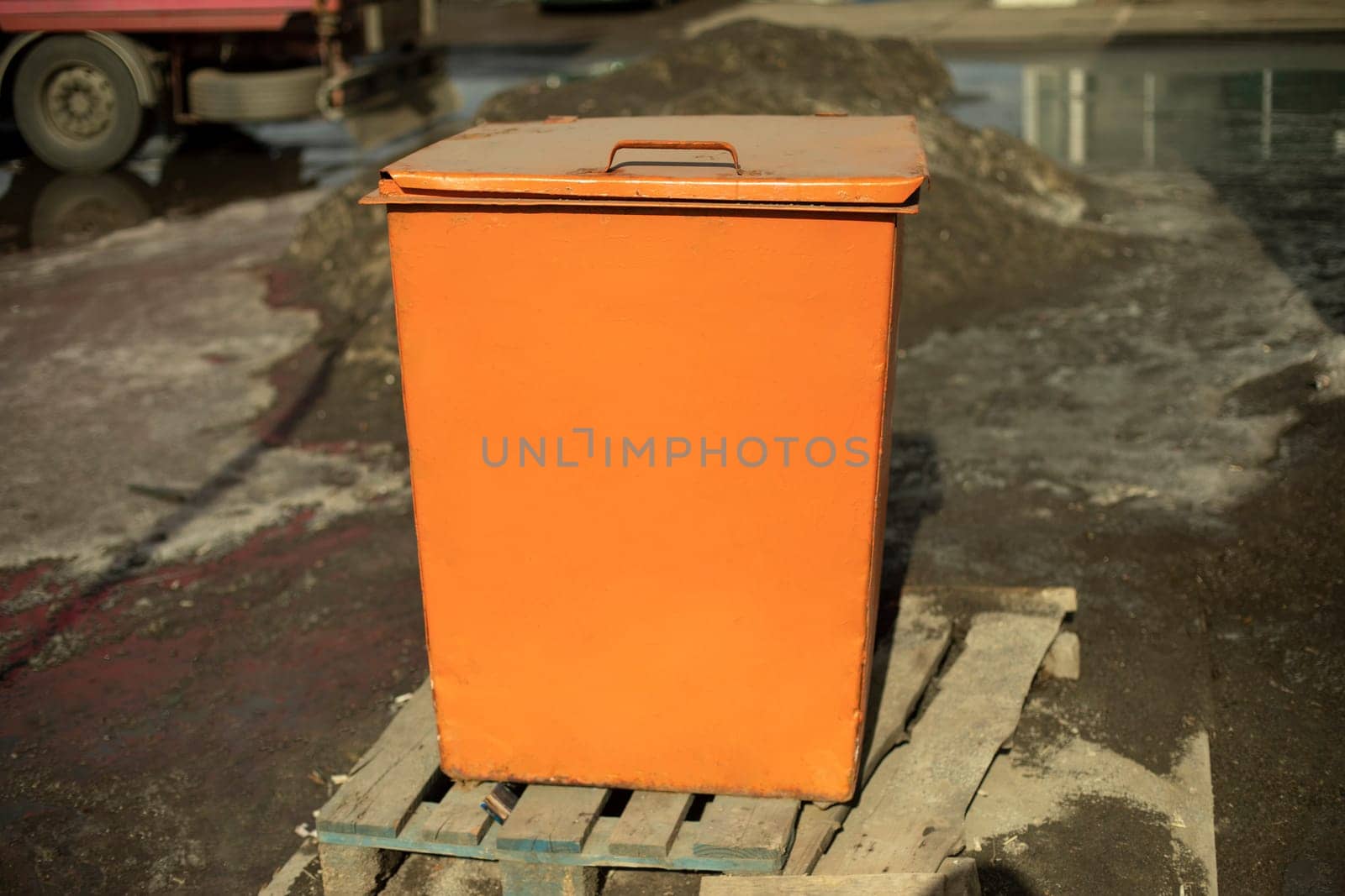 Orange waste tank. Dumpster. Steel tank in city.