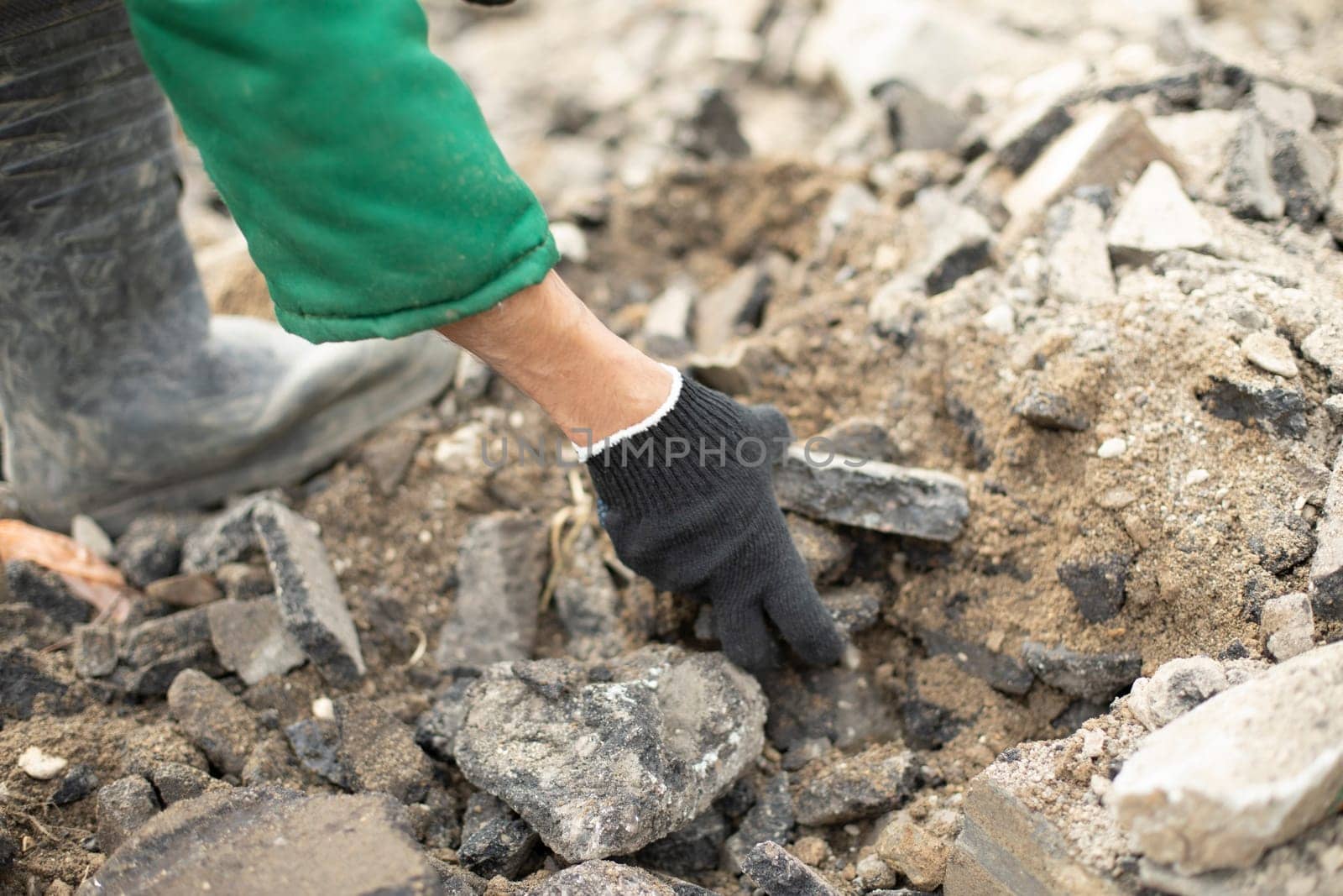 Worker takes stone. Cleaning of construction waste. Gloved hands.