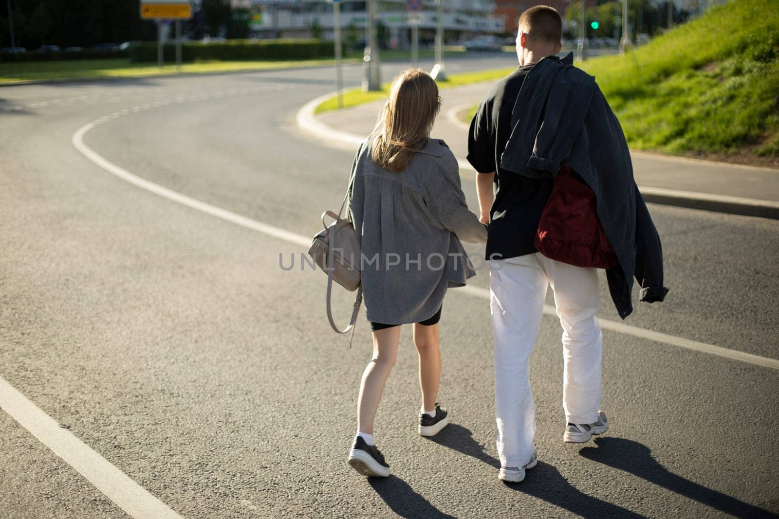 Guy and girl cross road. People are walking on road. People in city in summer. Couple in love on street.