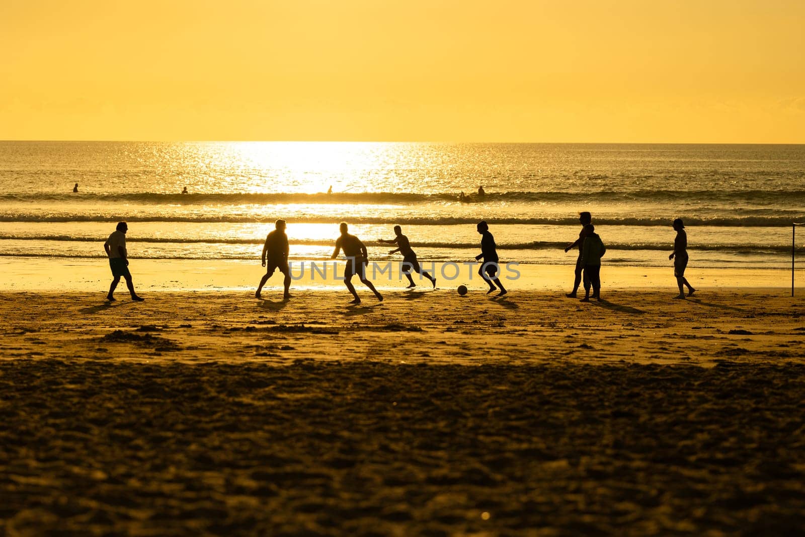 A group of people playing soccer on a beach