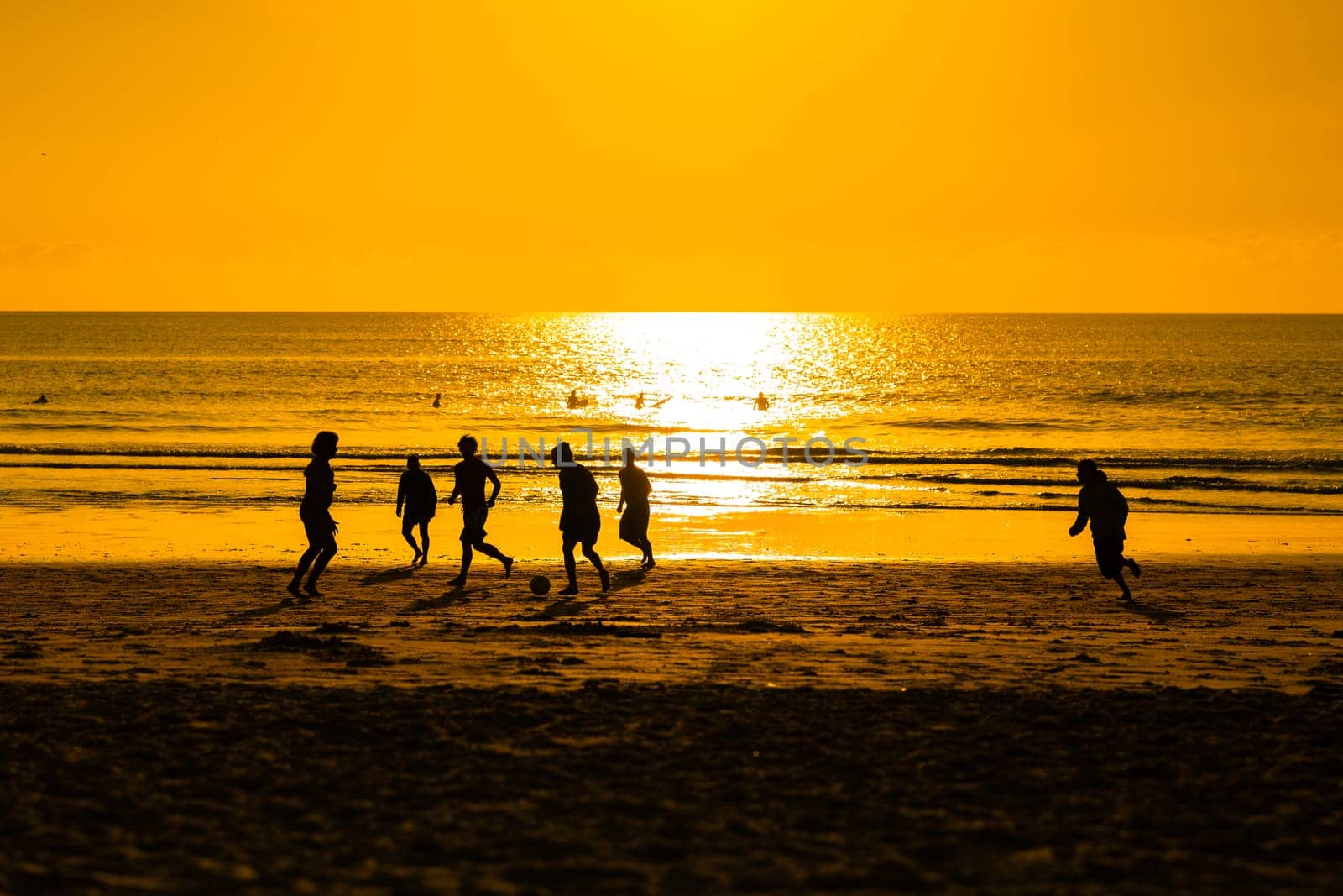 A group of people playing football on a beach
