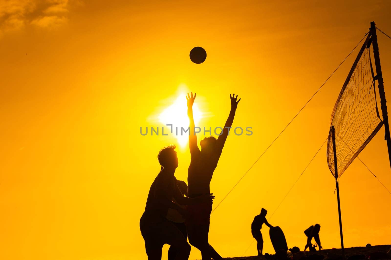 Young People Playing with a Ball at Sunset by the Ocean by Studia72