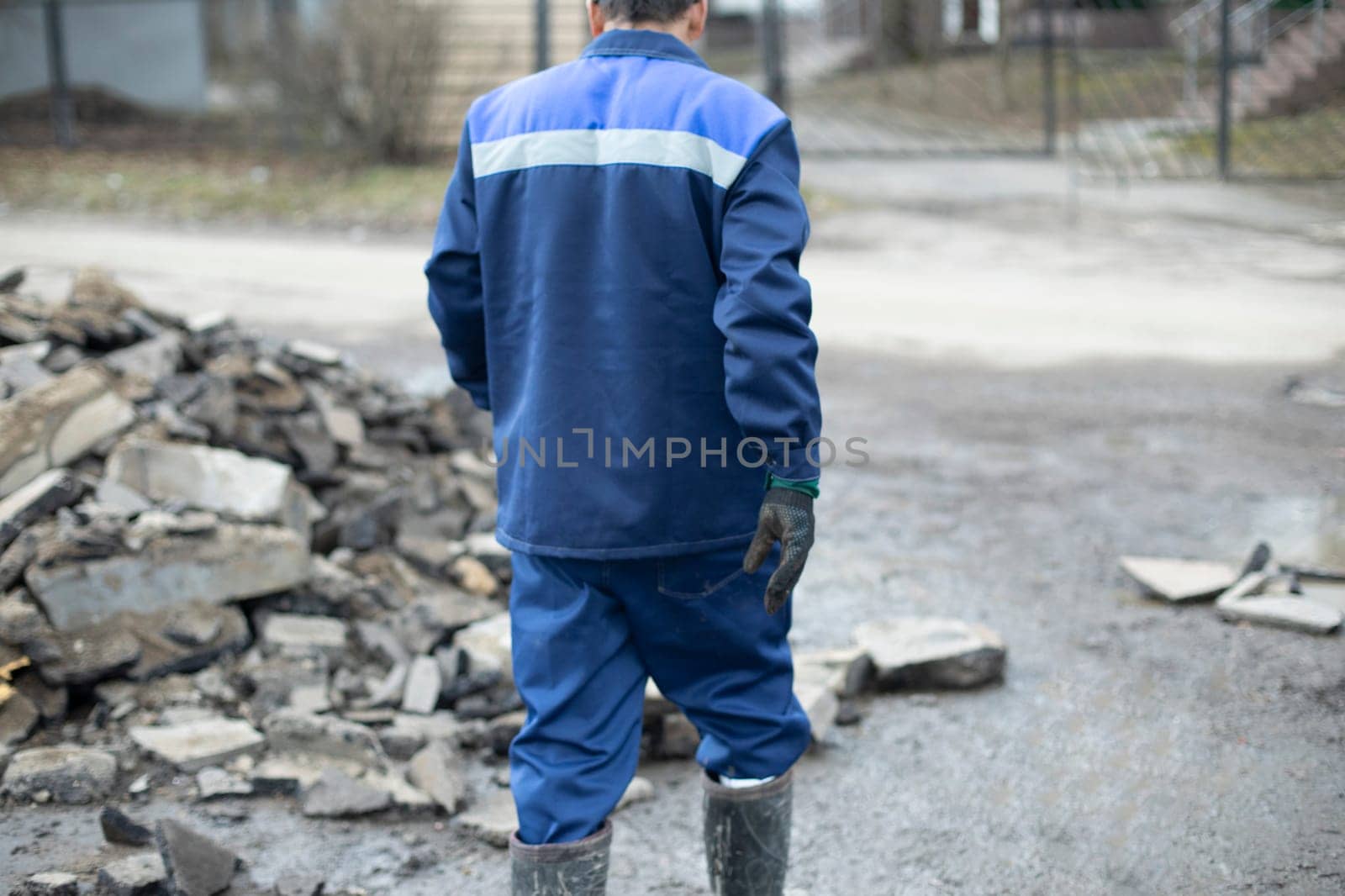 Worker in blue clothes. Road worker removes rocks. by OlegKopyov