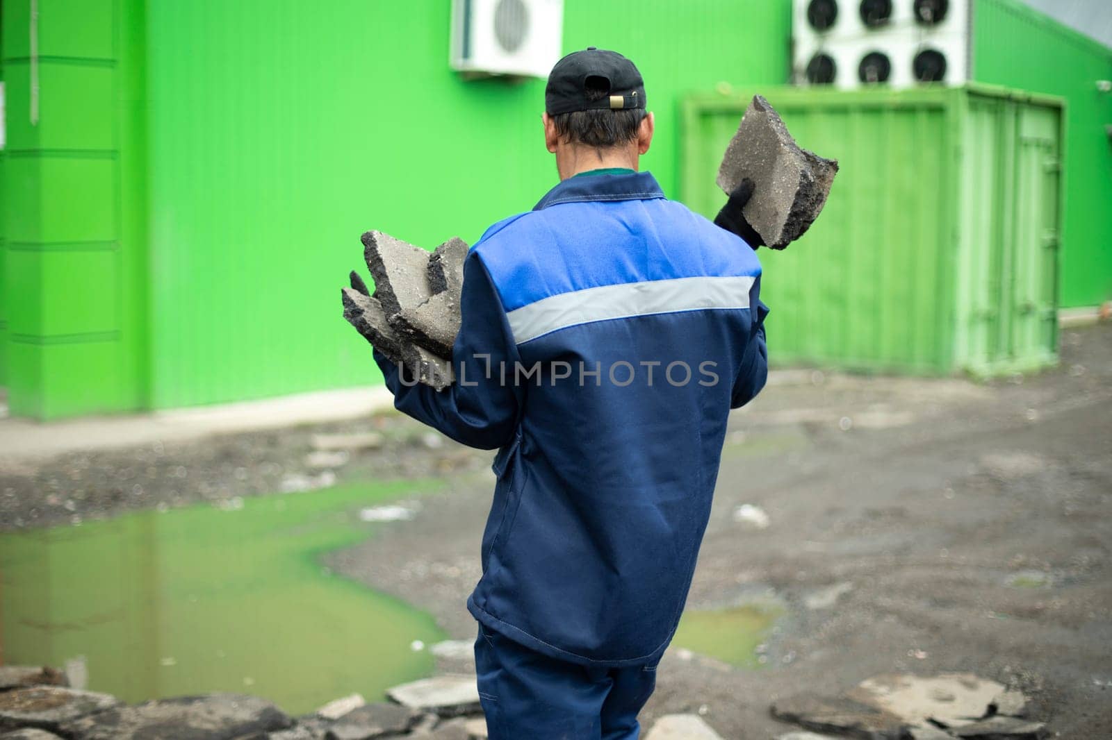 Worker in blue clothes. Road worker removes rocks. by OlegKopyov