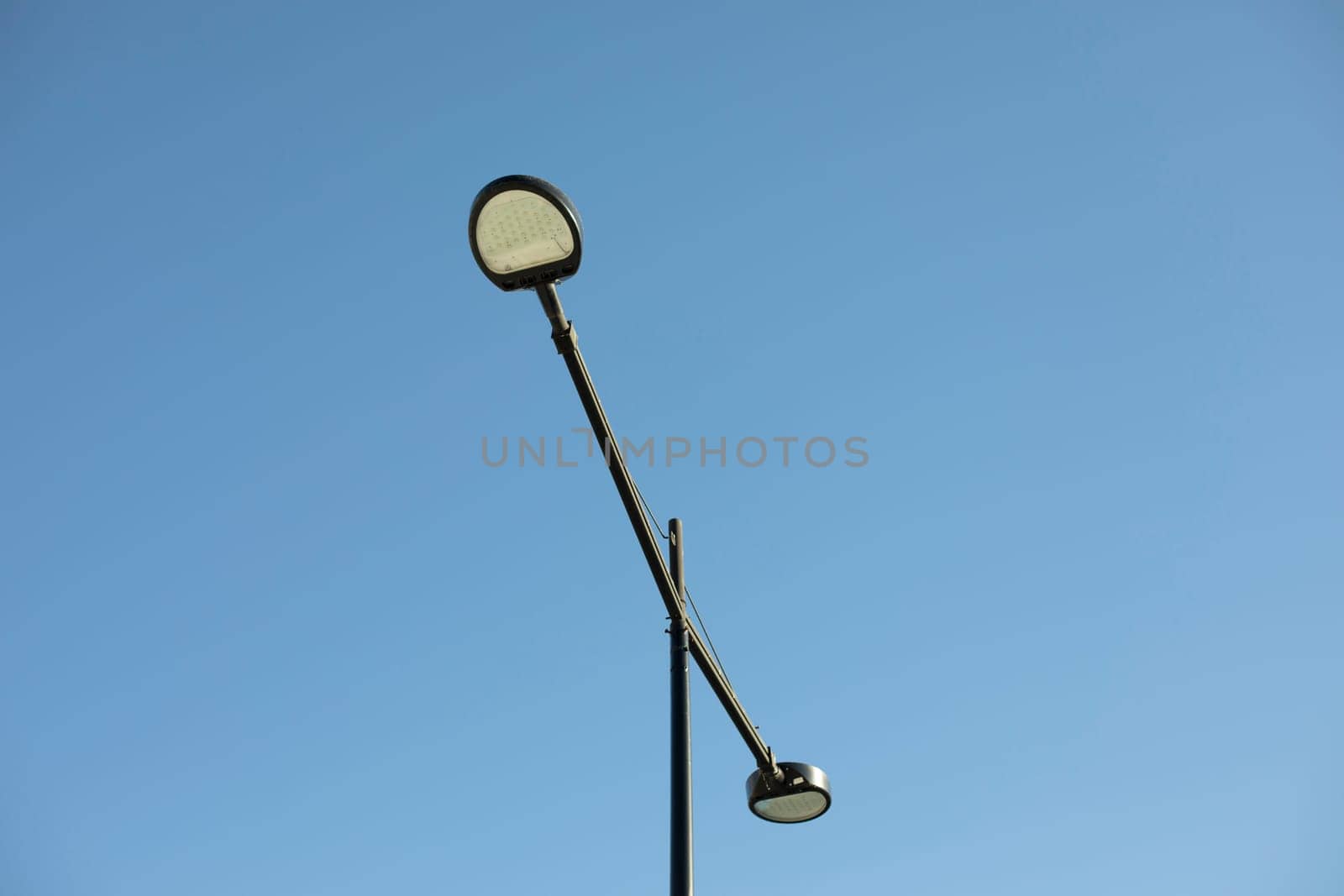 Pole with lamp against sky. Lighting fixture in city. Infrastructure details.