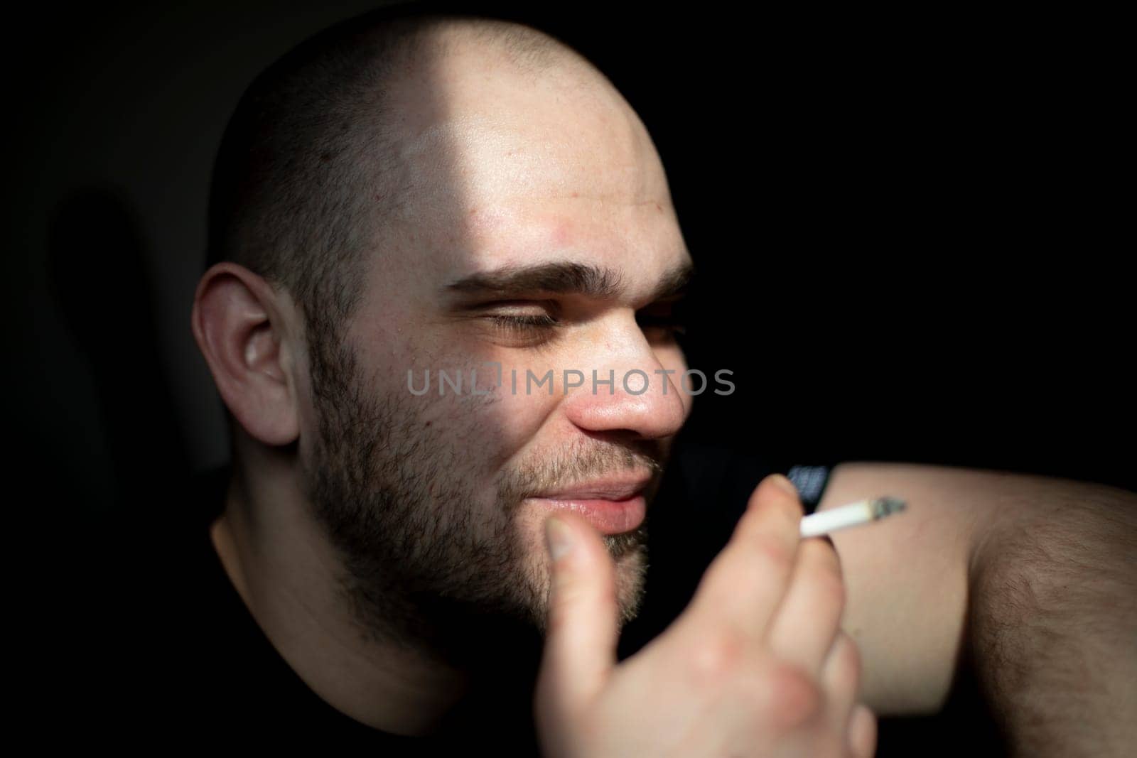 Guy smokes. Man with cigarette. Man is tired. Head in sunlight. After party.