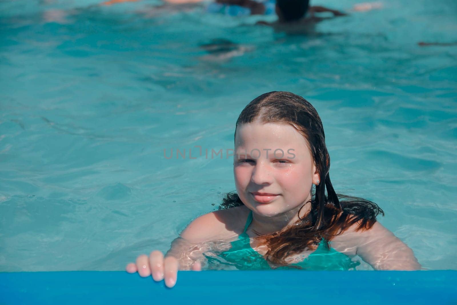 A little girl at the edge of the pool. Small child on the edge of the pool. Vibes of the 80s. Small girl in the pool. The concept of summer, water fun and summer fun.
