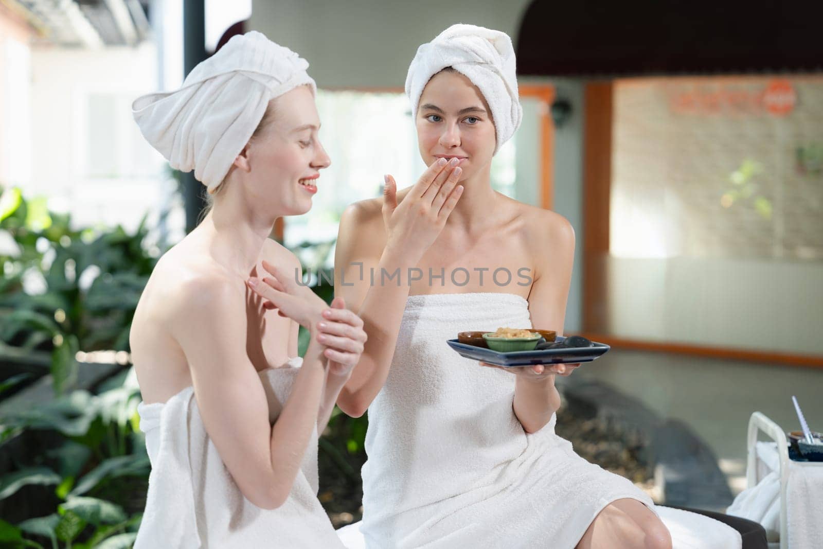 Two attractive woman in towel giggling during hold the herbal bowl. Tranquility. by biancoblue