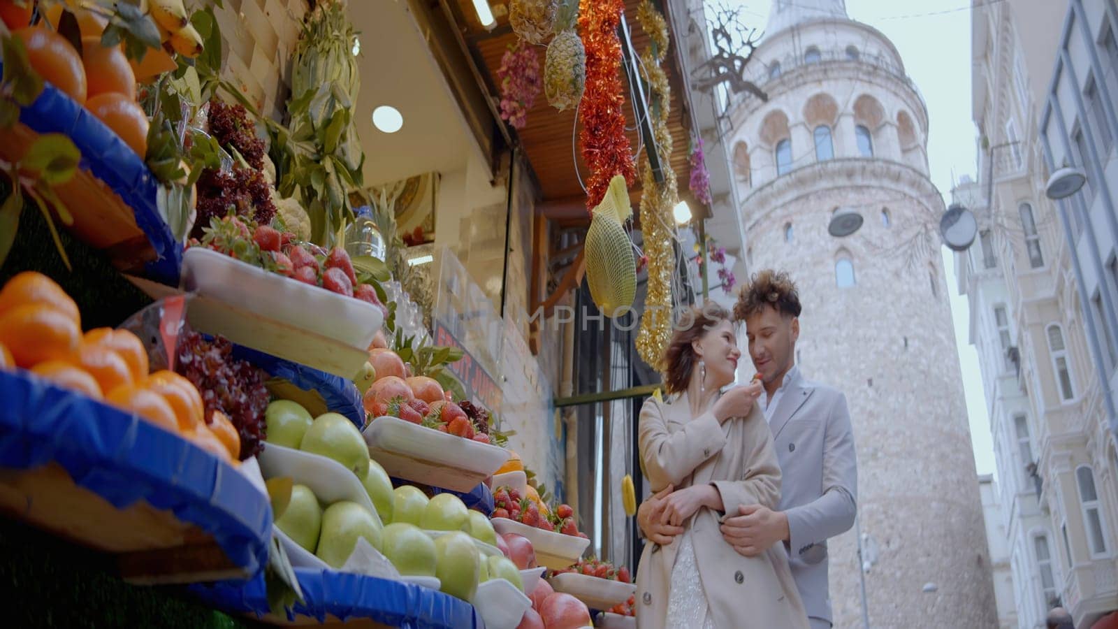 A young laughing couple. Action.An elegant couple is laughing next to fruit shops, a white tower and a blue sky can be seen from behind. High quality 4k footage