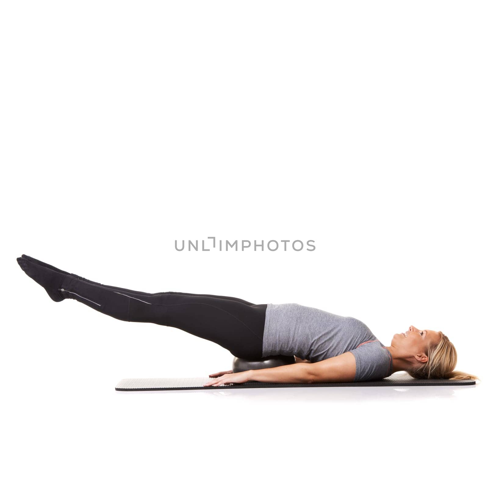 Woman, exercise ball and legs balance on yoga mat for workout performance, wellness or white background. Female person, gym equipment and fitness in studio for mockup space, challenge or stretching.