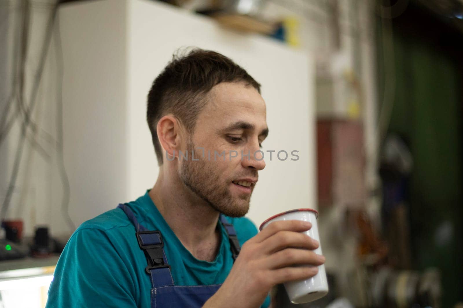 Guy drinks mug. Worker holds glass. Man drinks drink. Man at work.