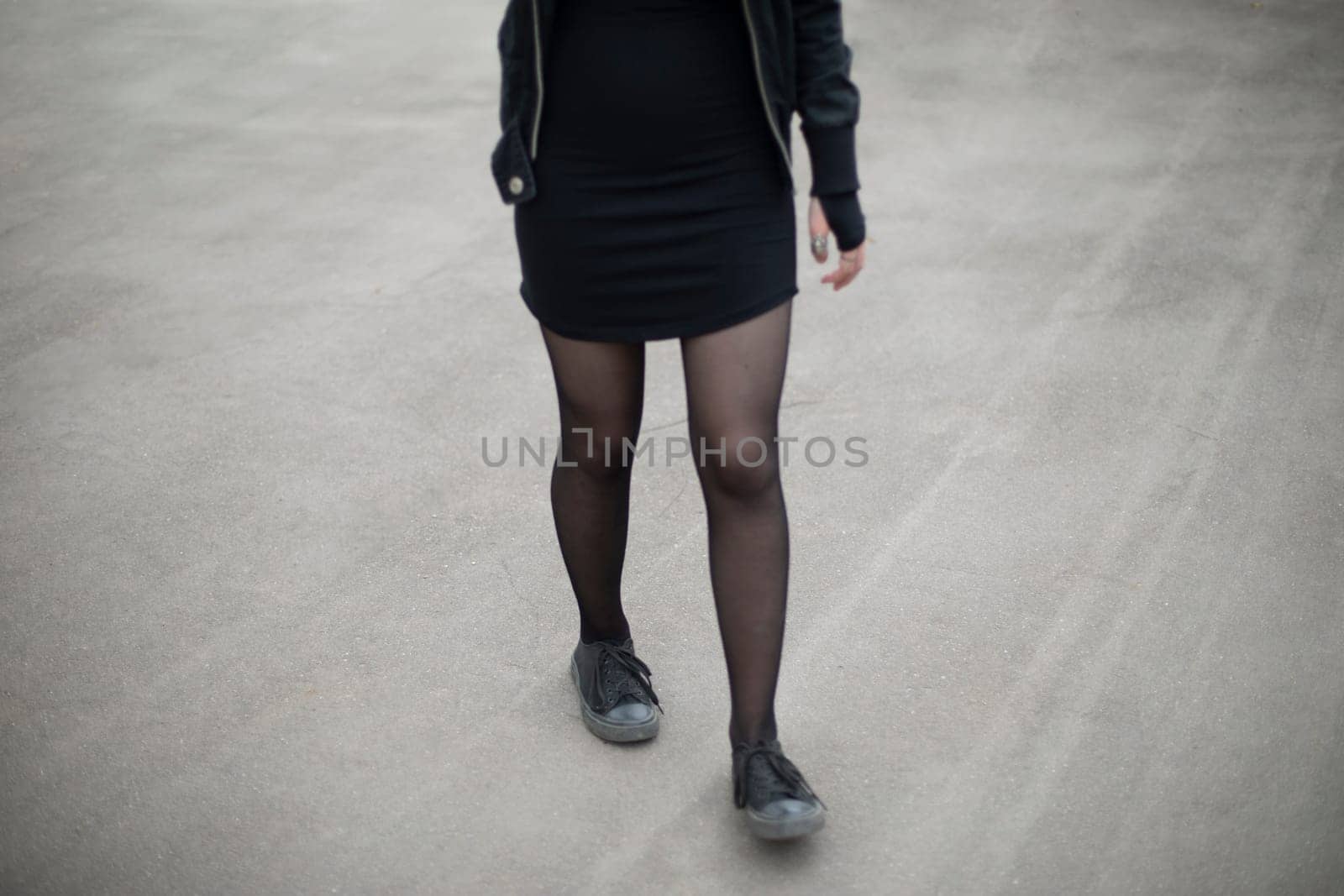 Black clothes of girl. Black tights. 2022 style. Women's legs. Student walks on asphalt.