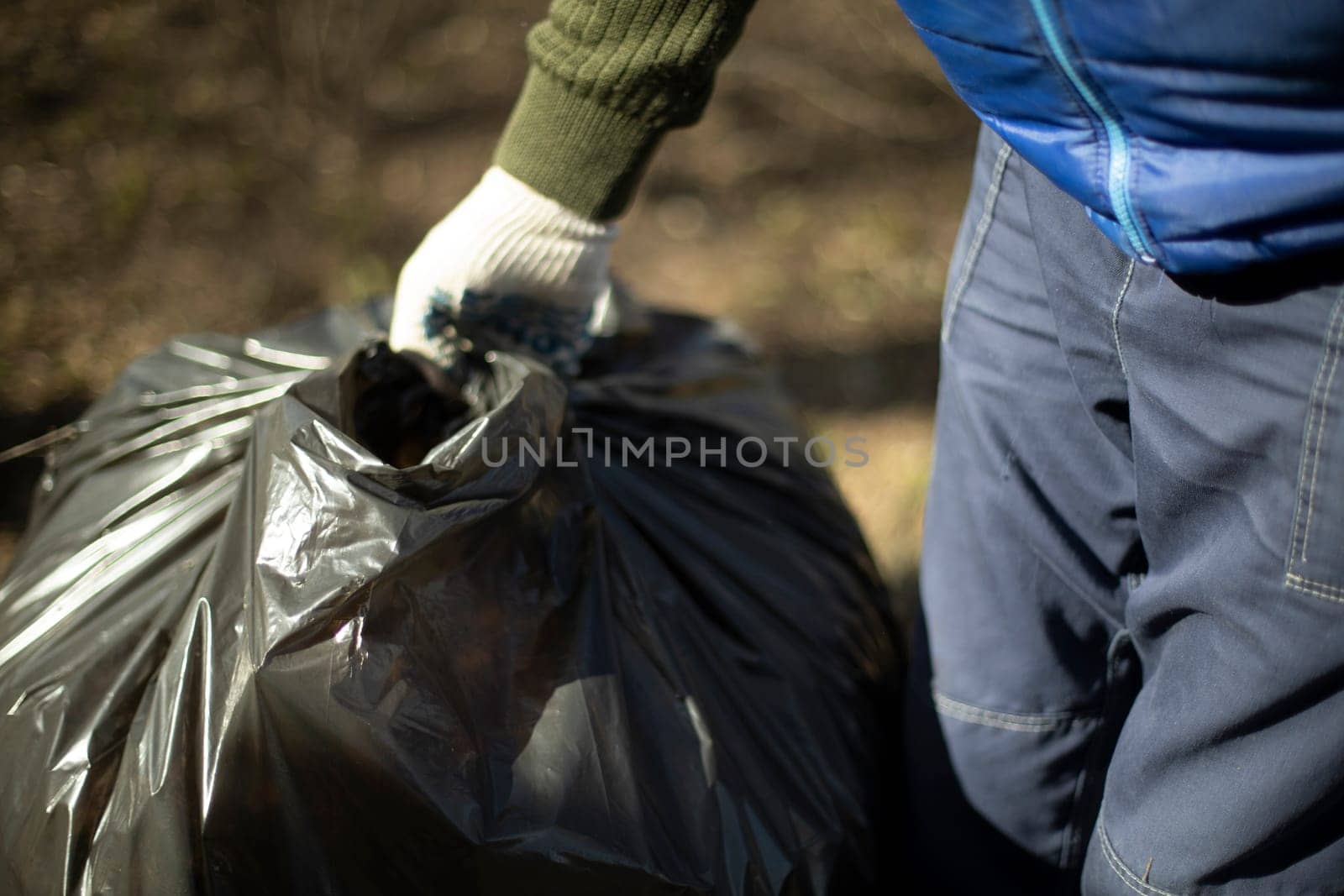 Garbage collection in bag. People clean up yard. Harvesting leaves in park.