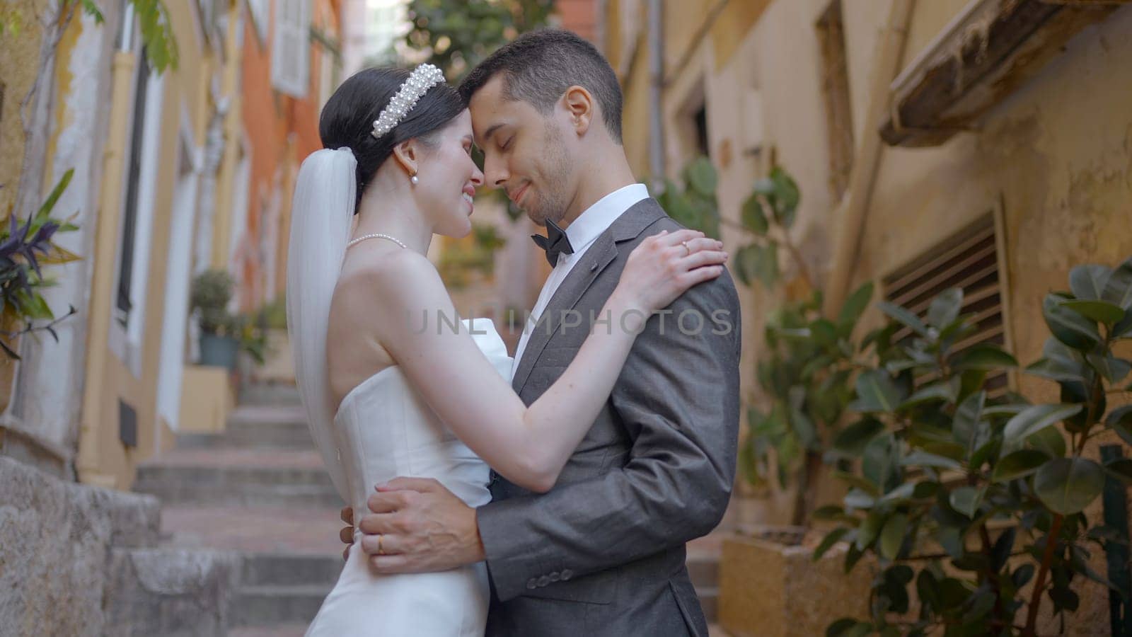 Beautiful couple of newlyweds gently embrace. Action. Beautiful elegant couple in outfits are sexually embracing. Newlyweds in love embrace on stairs of old town.