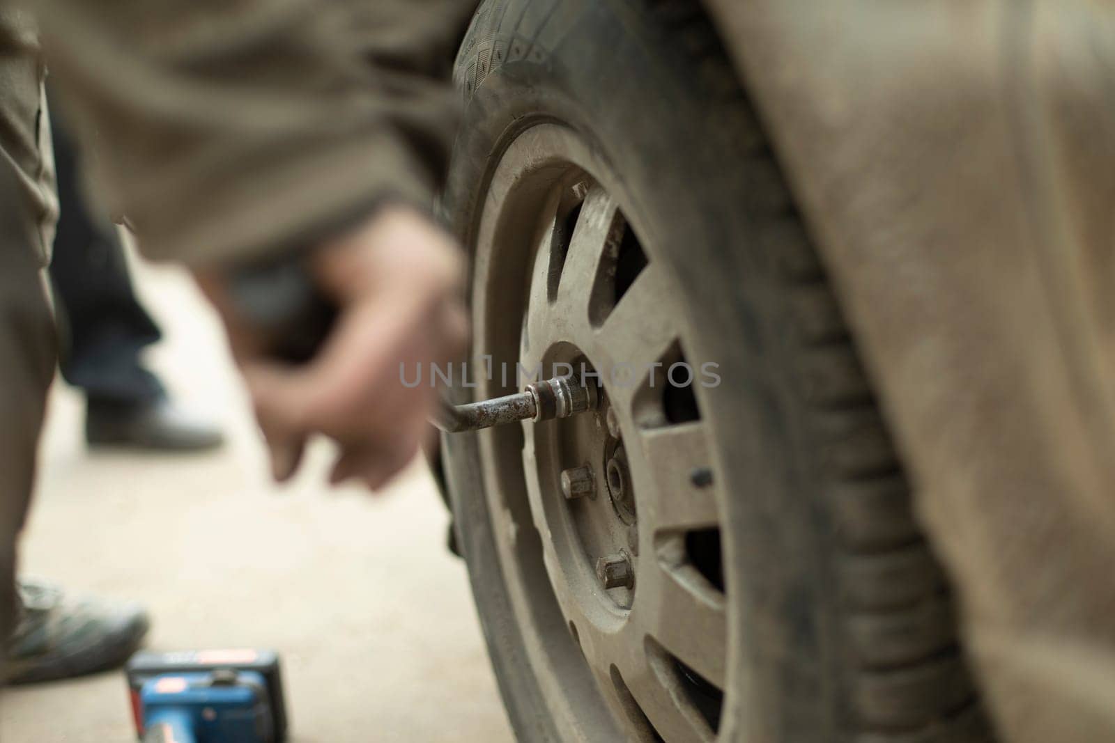 Nut on wheel. Lever to replace wheel on car. Hand holds key. Spanner.