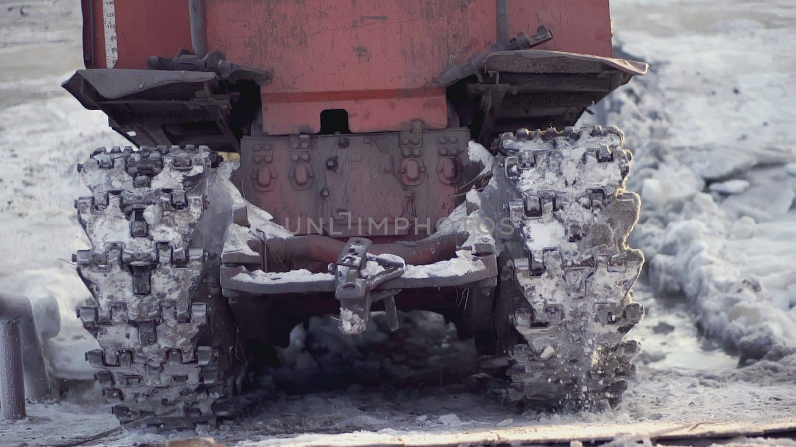 The back of a large technical machine. CLIP. The wheels drive the car back through the snow. Heavy equipment rides in the snow on metal tracks.