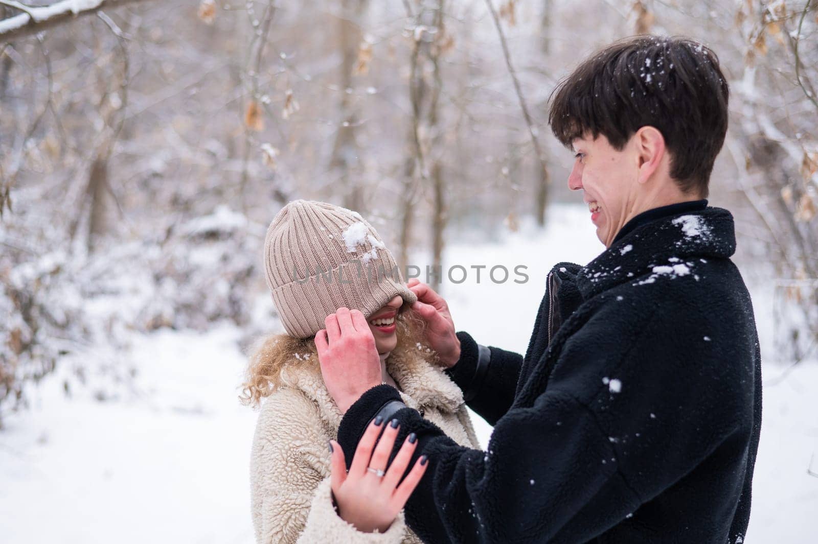 A young couple walks in the park in winter. Guy and girl fooling around on the street