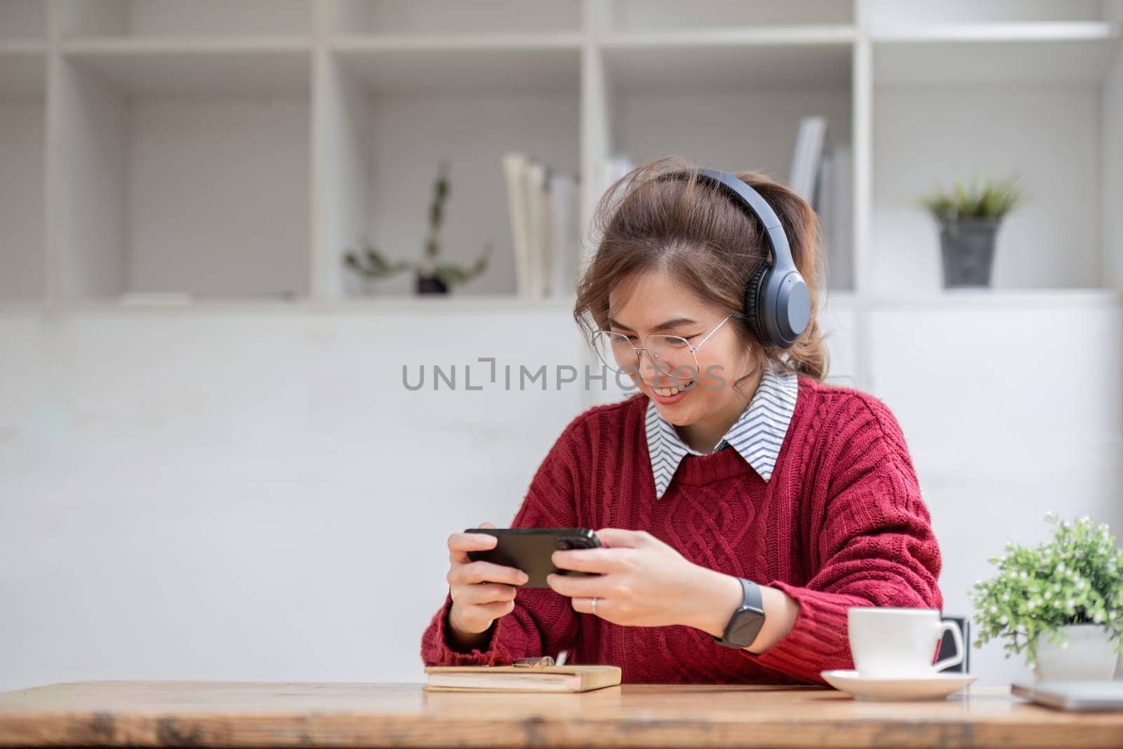 Excited Asian woman playing online game on her smartphone with live broadcasting on internet. cell telephone technology e-commerce concept.