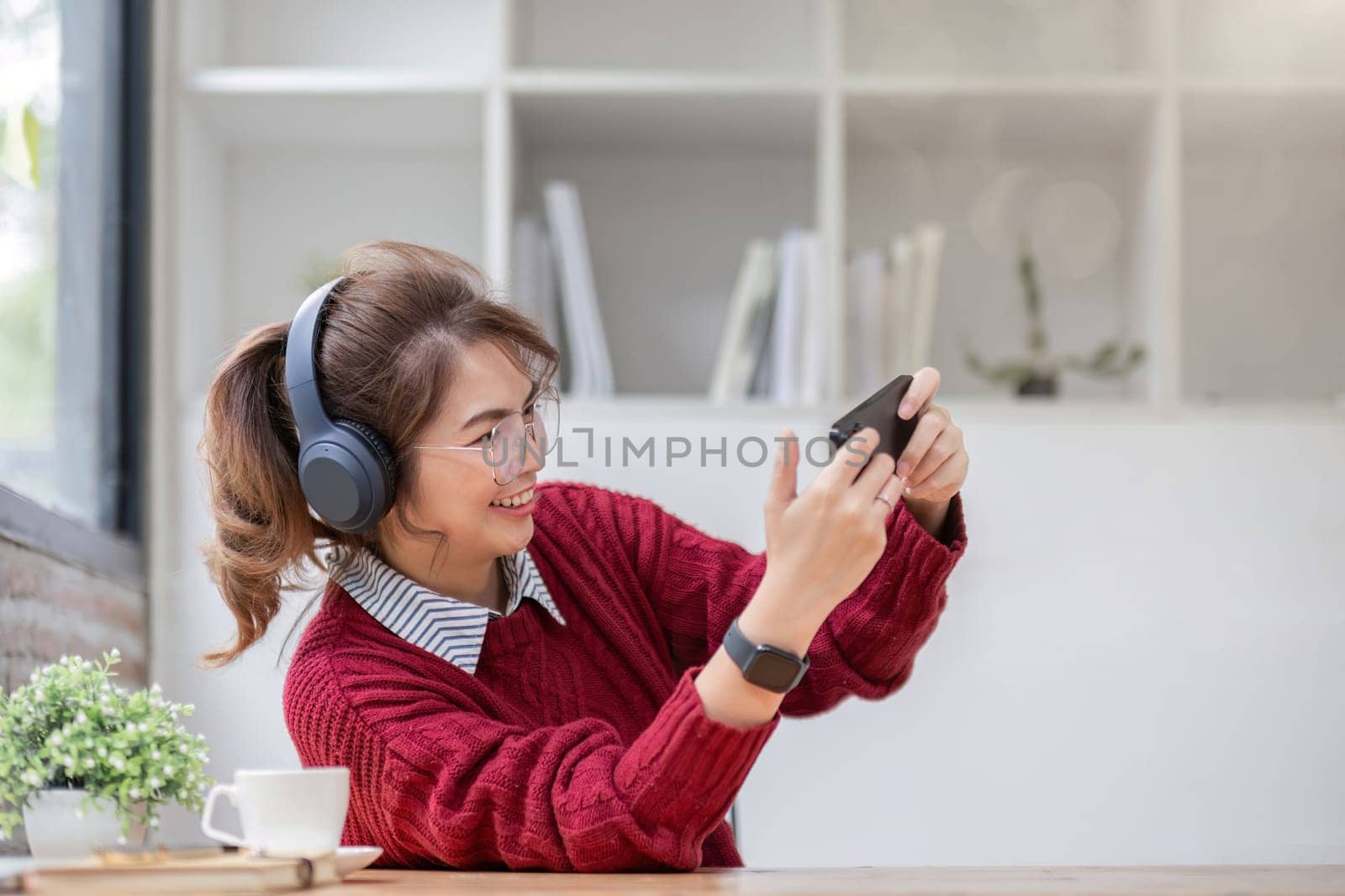 Excited Asian woman playing online game on her smartphone with live broadcasting on internet. cell telephone technology e-commerce concept by wichayada