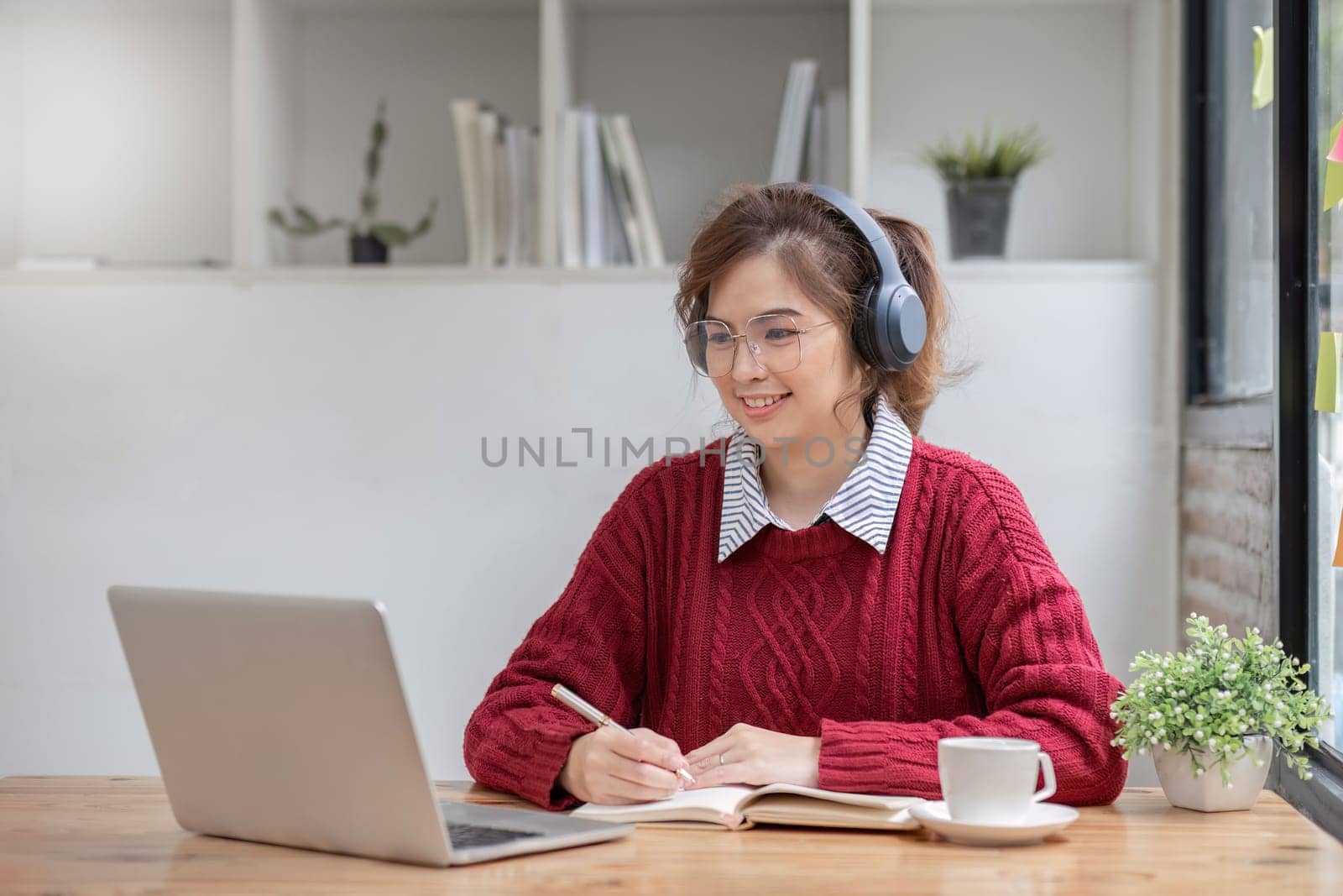 Asian female student study online in class, study online, wearing headphones, watching video call, zooming, happy asian female learning language online with computer laptop. by wichayada