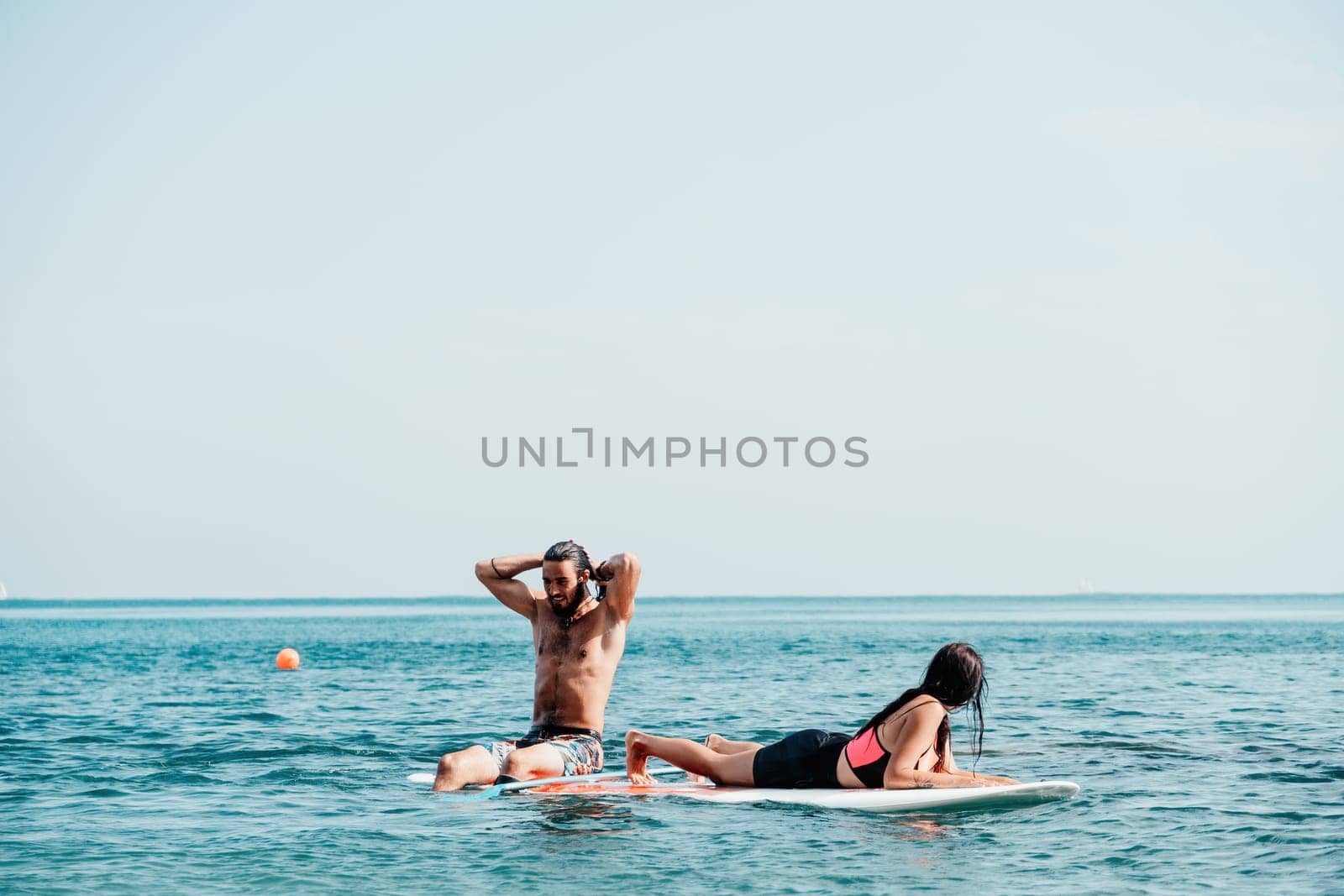 Sea woman and man on sup. Silhouette of happy young woman and man, surfing on SUP board, confident paddling through water surface. Idyllic sunset. Active lifestyle at sea or river