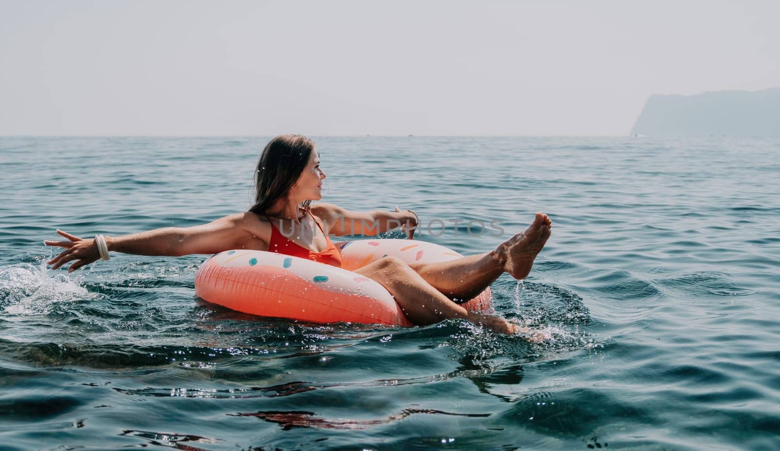 Woman summer sea. Happy woman swimming with inflatable donut on the beach in summer sunny day, surrounded by volcanic mountains. Summer vacation concept. by panophotograph