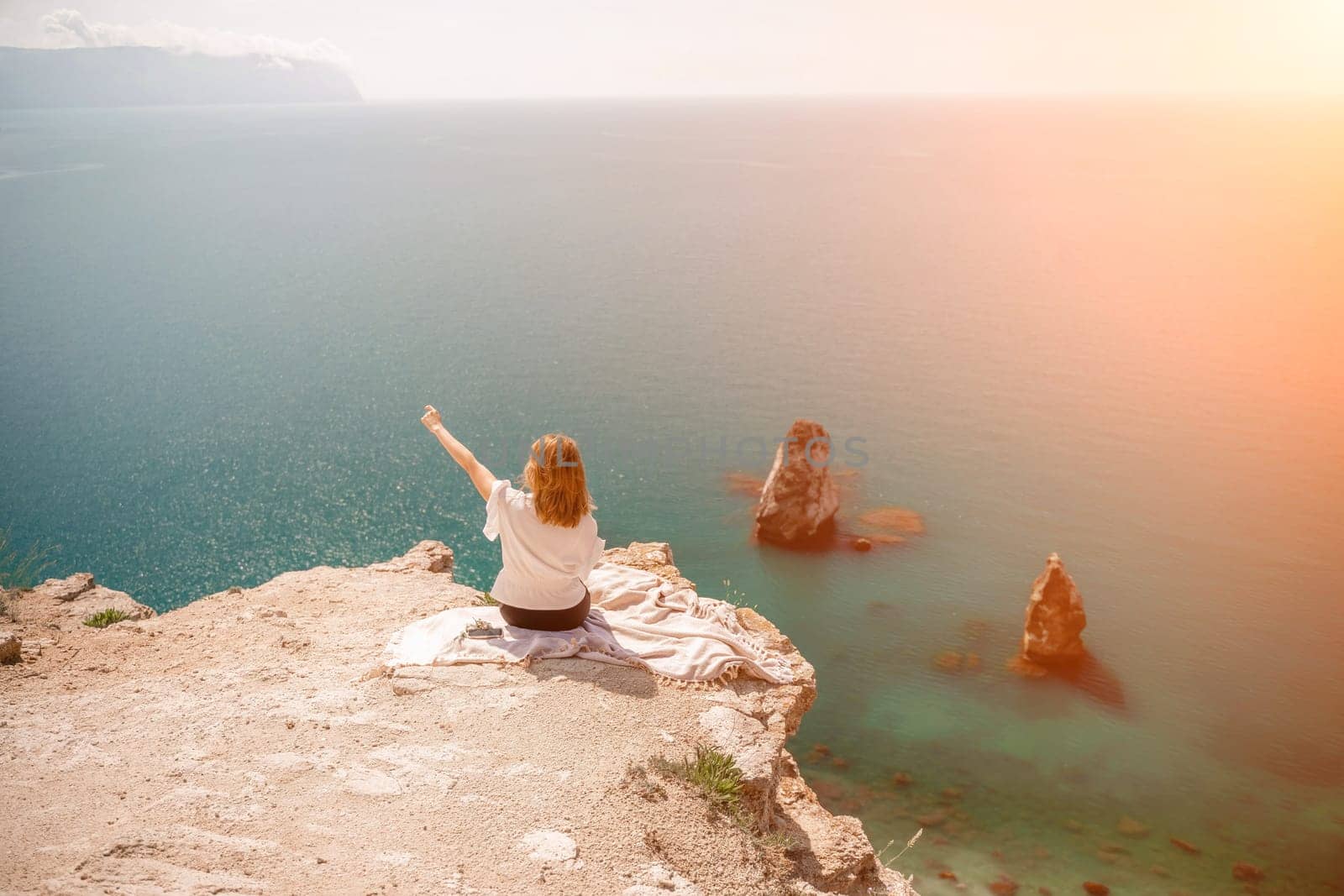 Freelance woman working on a laptop by the sea, typing away on the keyboard while enjoying the beautiful view, highlighting the idea of remote work