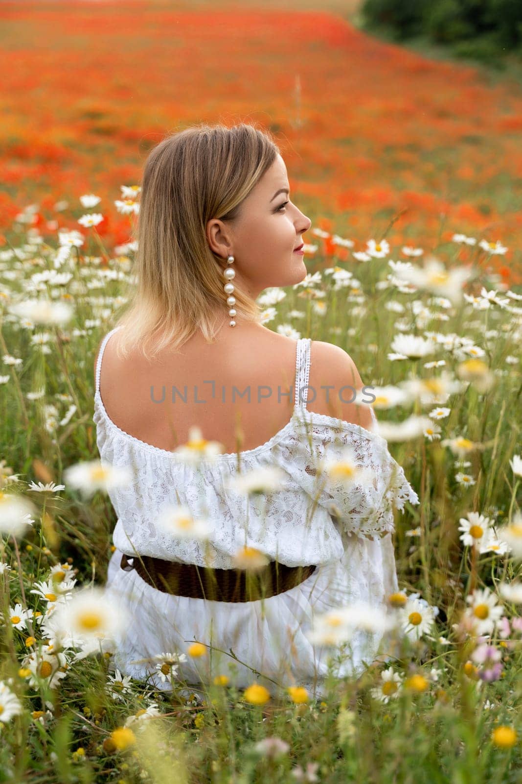 A woman sits in a chamomile field, dressed in a white dress by Matiunina