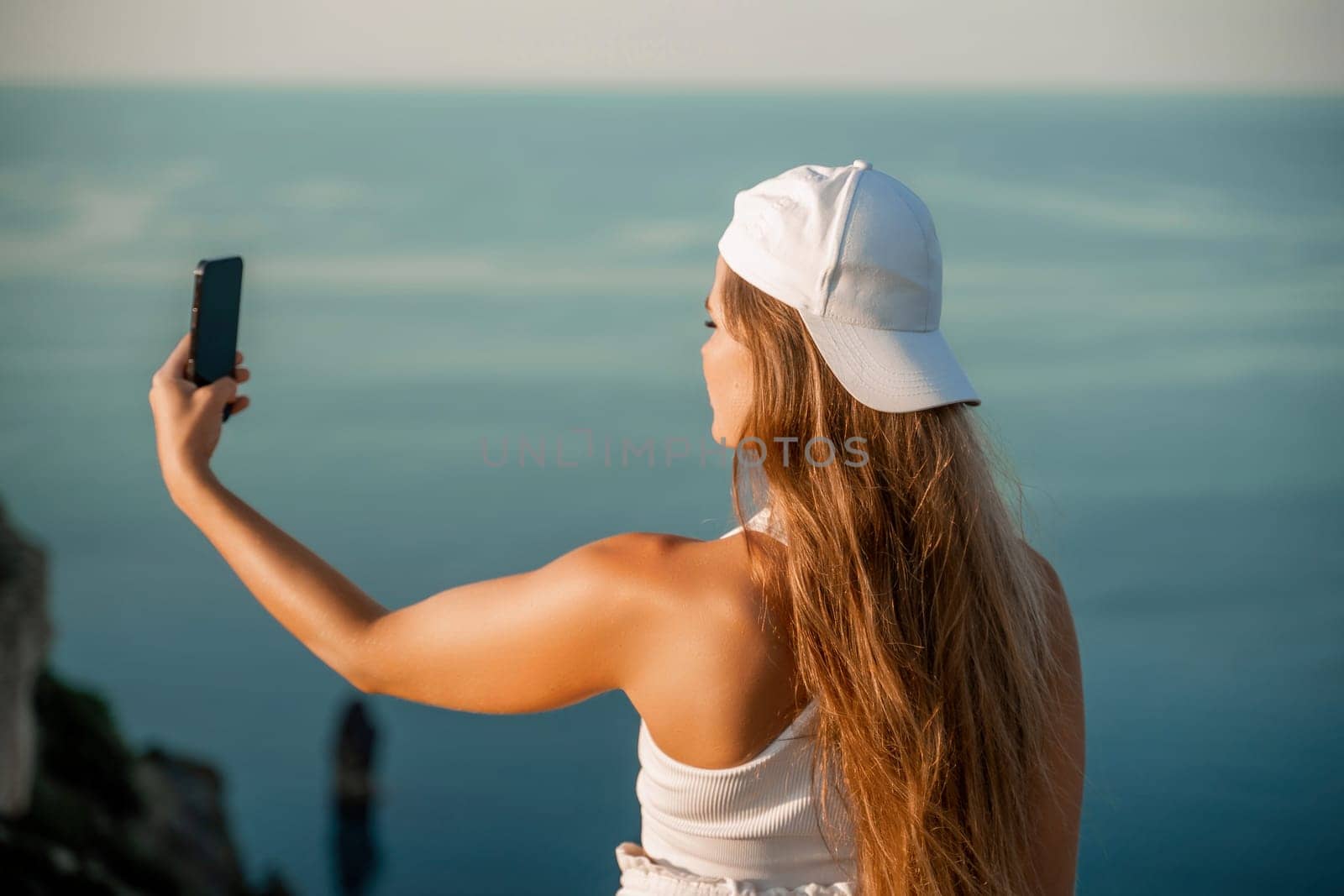 Selfie woman in cap and tank top making selfie shot mobile phone post photo social network outdoors on sea background beach people vacation lifestyle travel concept