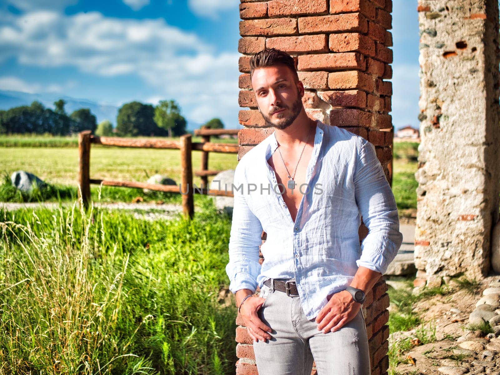 A man leaning against a brick wall in front of a corn field