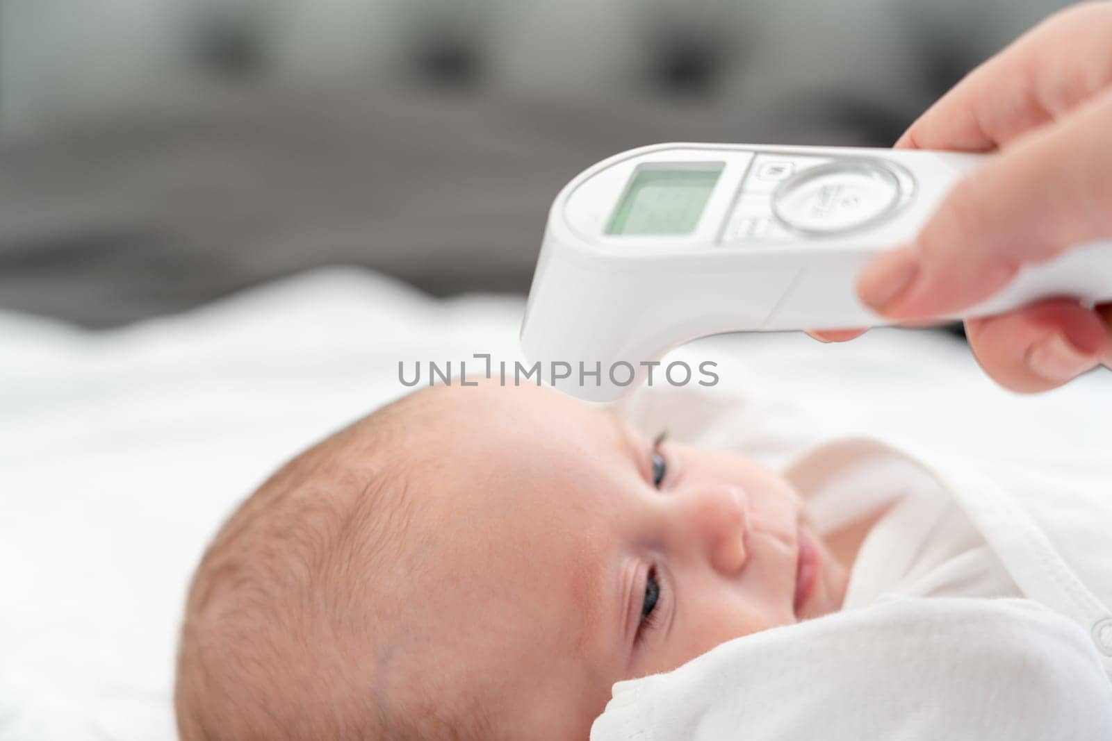 A dedicated mother checks the temperature of her infant baby, using a reliable digital thermometer