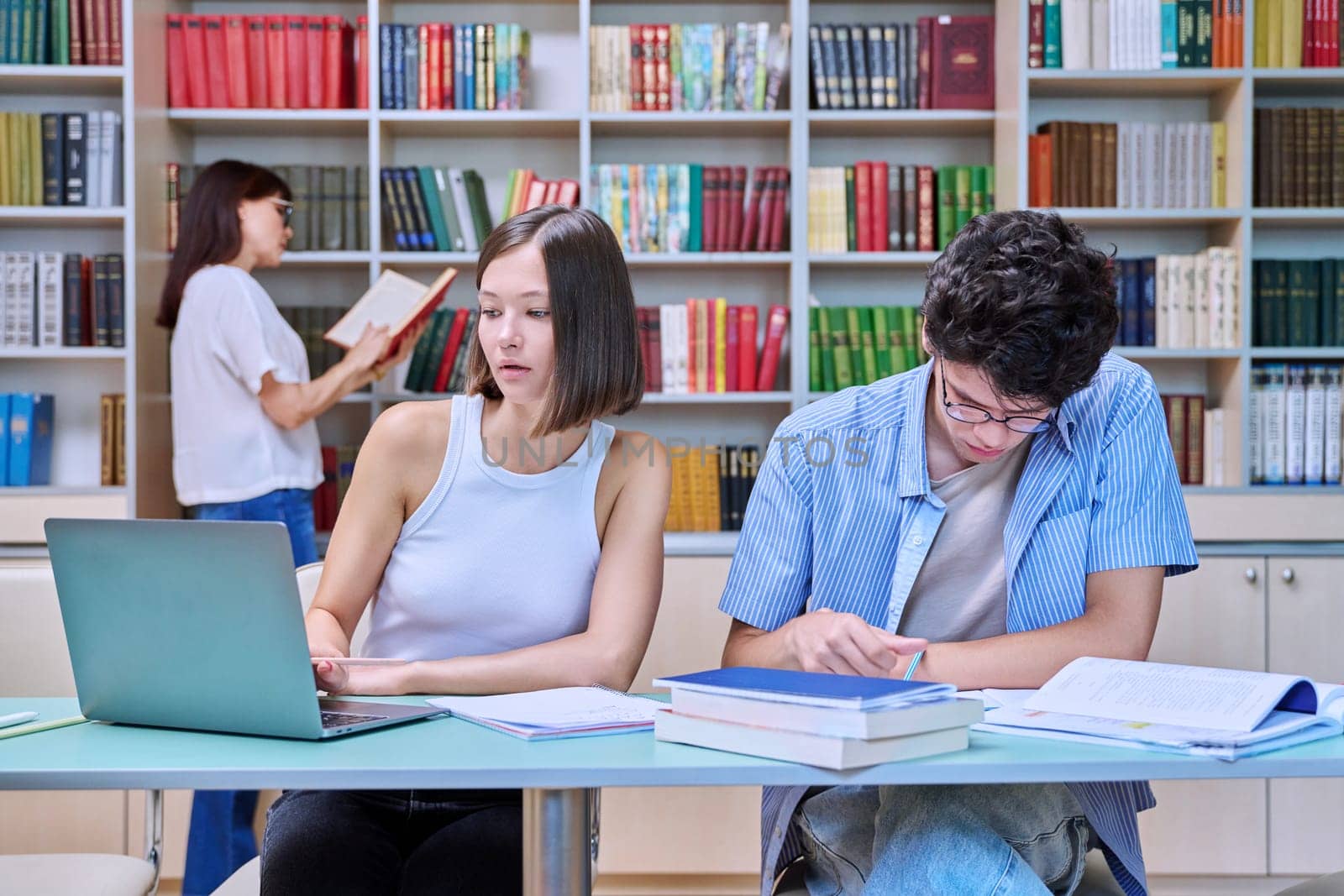 Two students sitting in college library, studying, preparing for exams by VH-studio