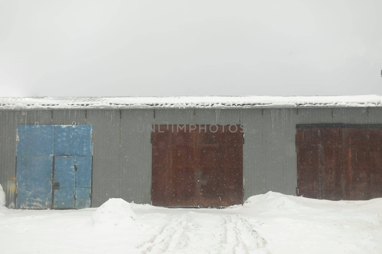 Hangar in winter. Rusty gates. Workshop is outside. Industrial zone. Entrance to territory.