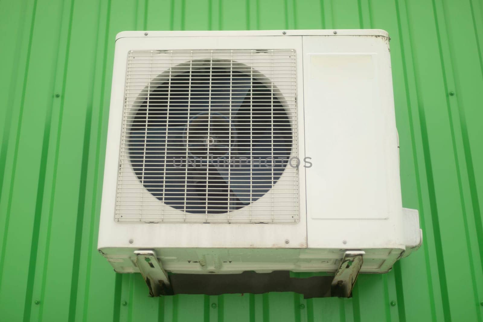 Air conditioning on wall. White air conditioning on building. Cooling system. Fan with grille.