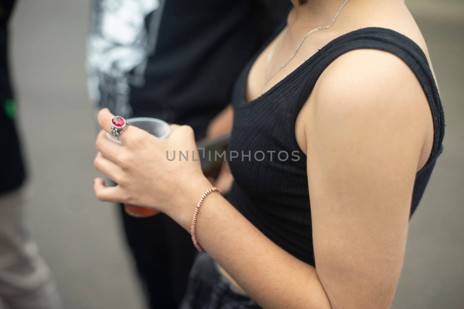 Girl hand. Summer clothes. Bare shoulder. Student holds something in her hand. Young skin of hand.