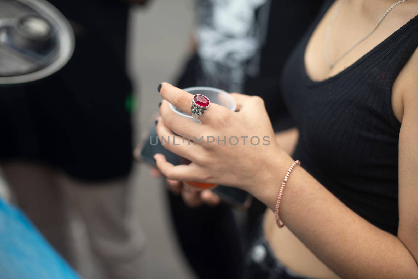 Girl holding glass. Drink on street. Girl in summer clothes. Bare hand.