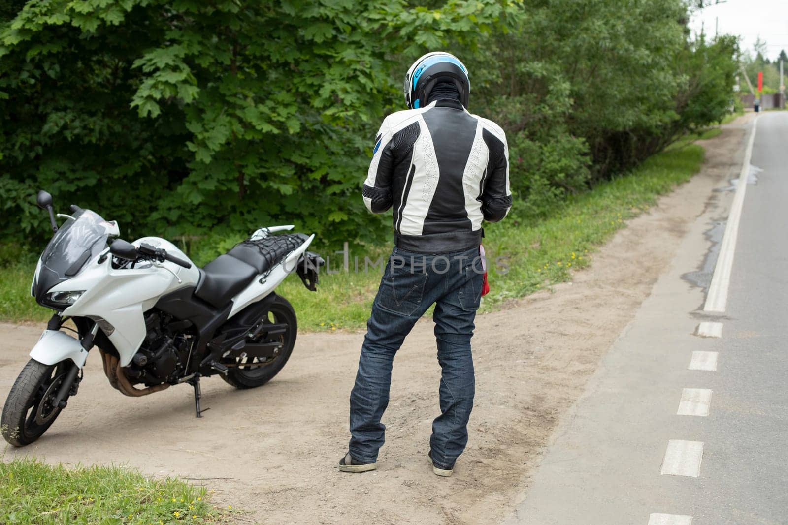 Motorcyclist is standing on road. Sports bike. Man in helmet. Details of traveling on motorcycle.