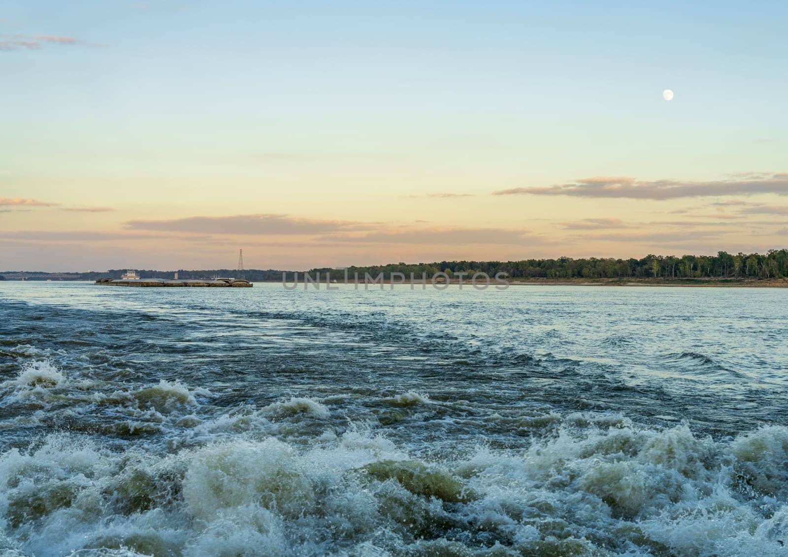 Large river barge loaded with grain sailing down Mississippi river near Natchez at dusk