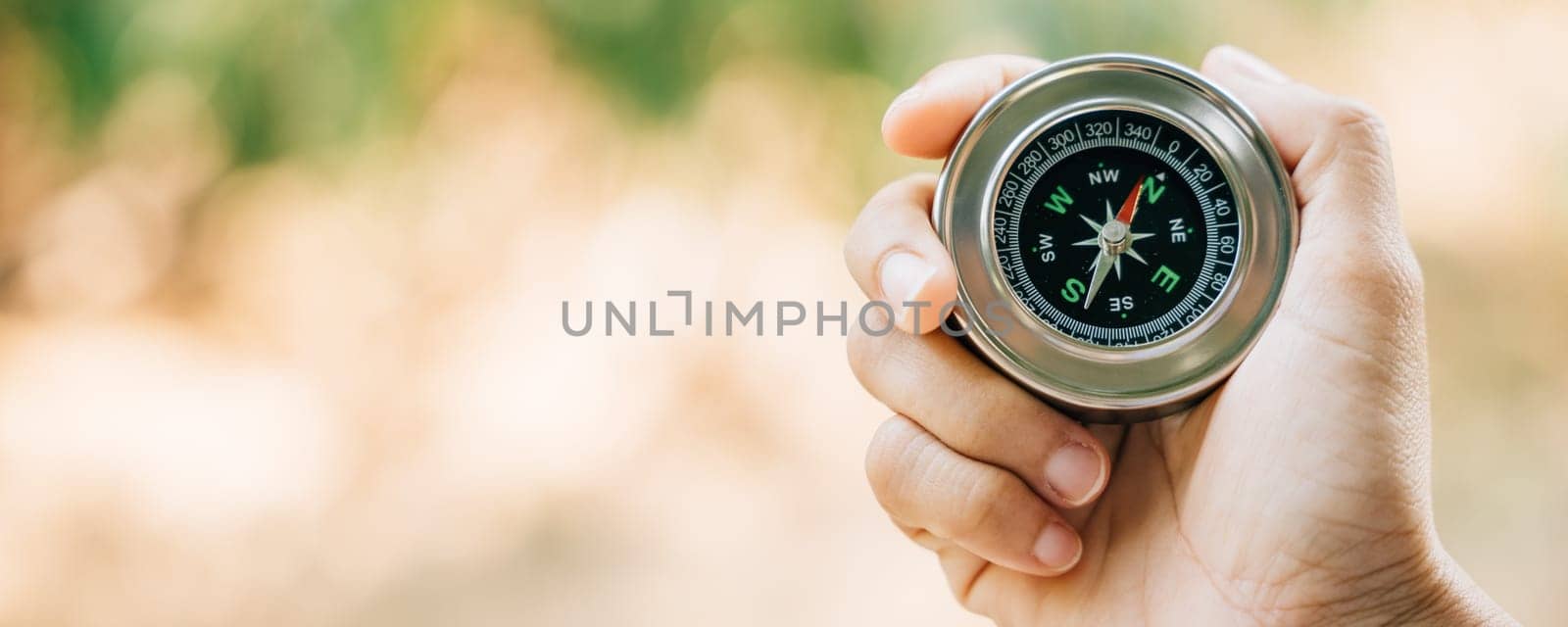 A traveler hand cradles a compass in a park symbolizing the quest for direction and guidance. Amidst nature beauty the compass signifies exploration and discovery.