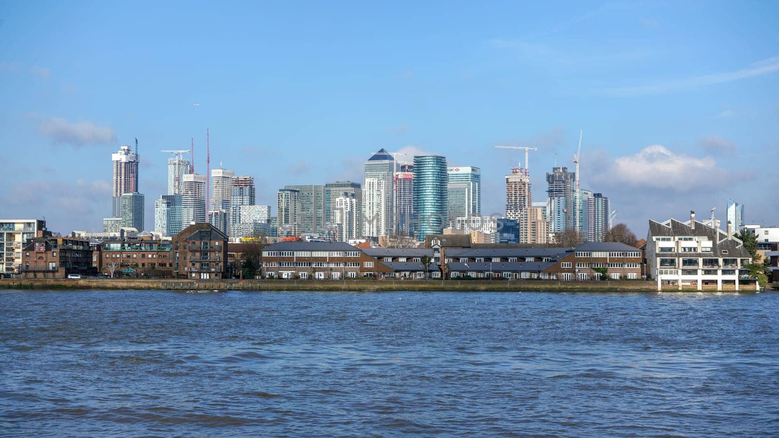 London, United Kingdom - February 03, 2019: View over river Thames on Canary Wharf, major financial district, with residential buildings in foreground. 