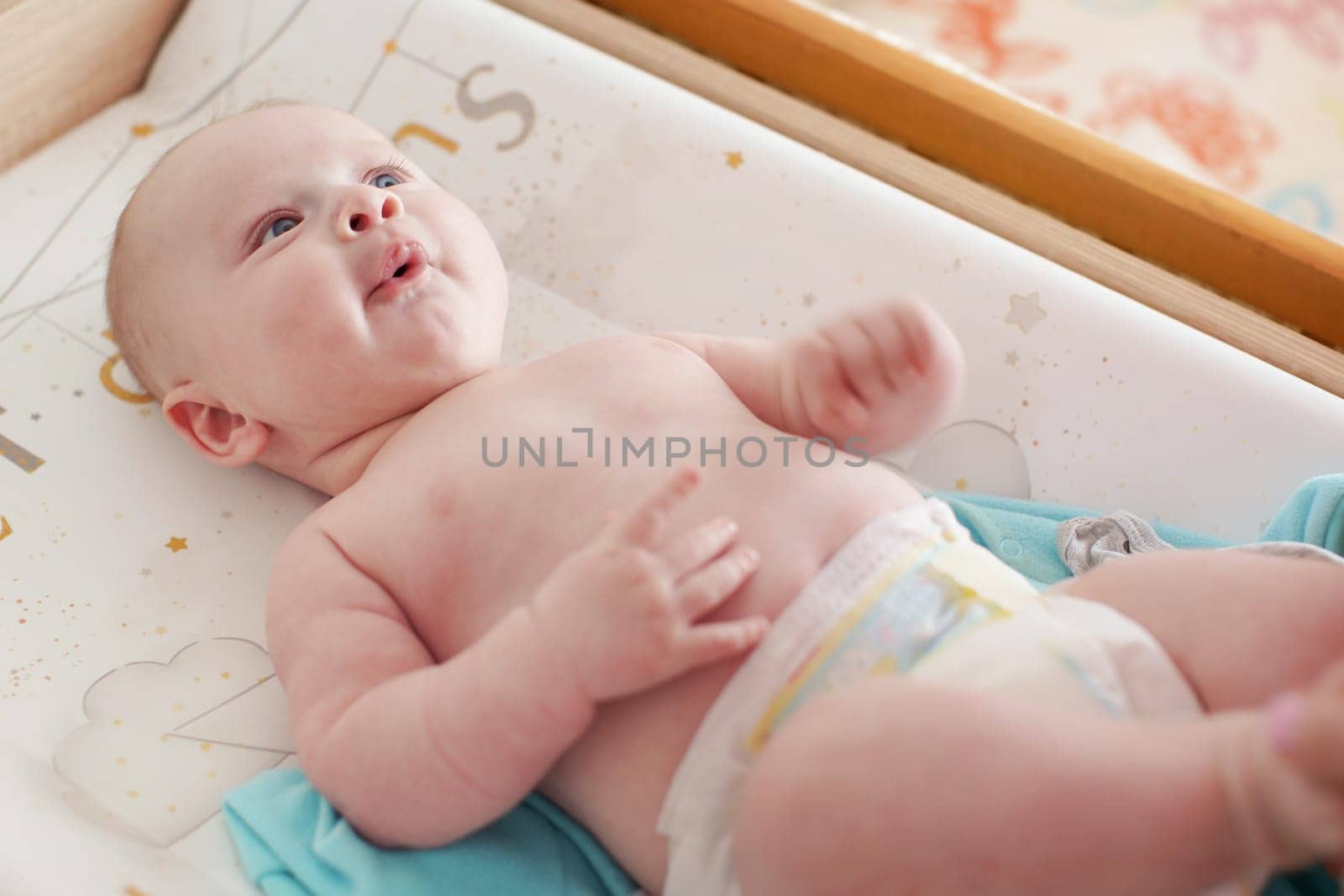 4 months old infant boy lying on changing desk, by Ivanko