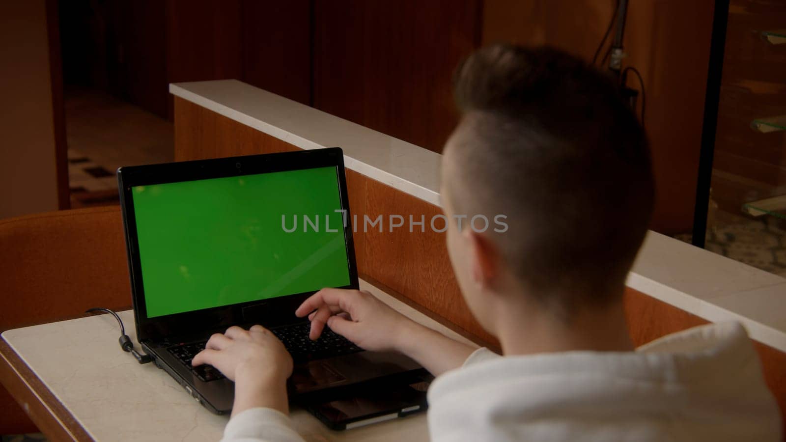 Back view business man working on laptop with green screen. Stock footage. Young man working at the computer with chroma key