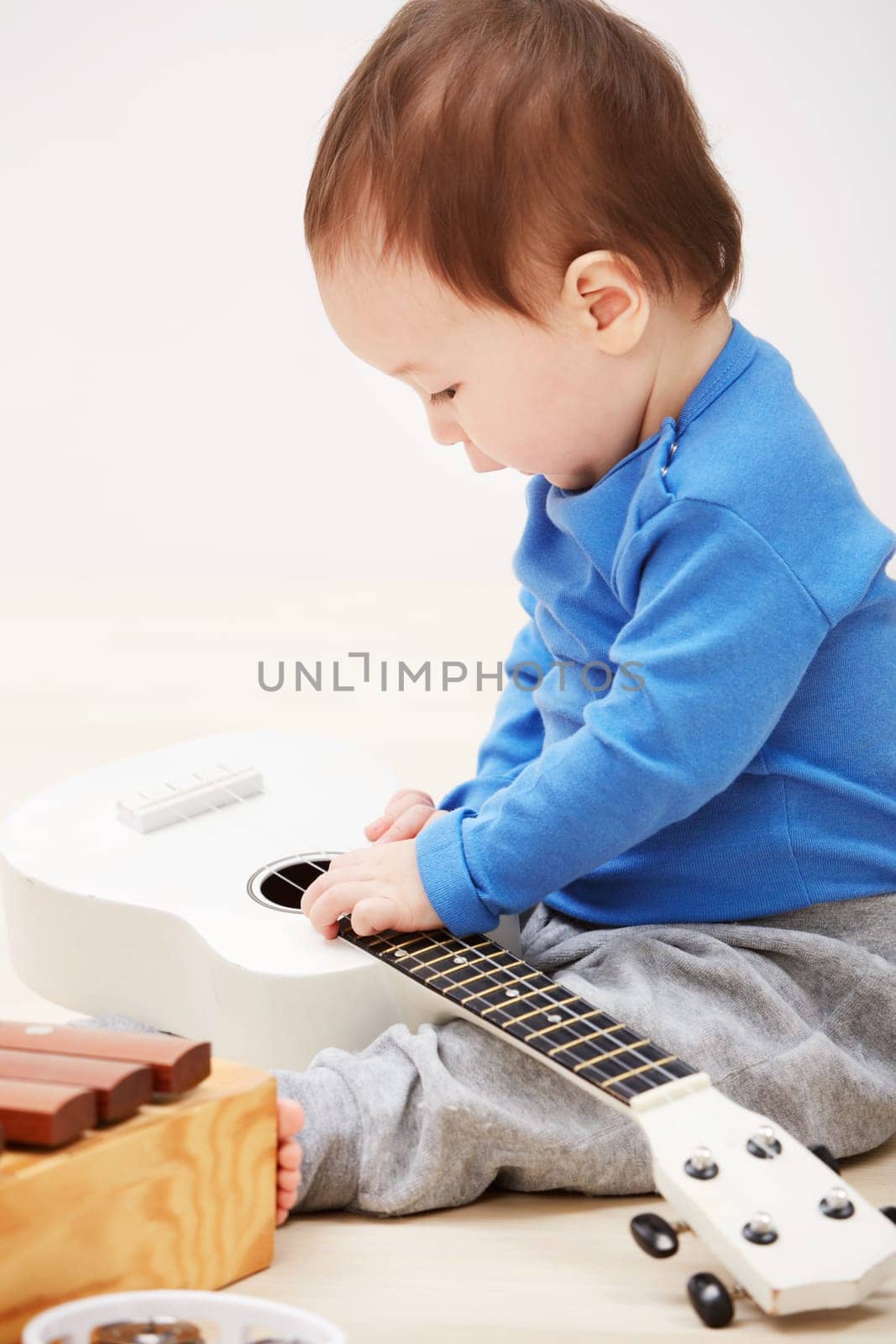 Baby, guitar toys and play in home for entertainment joy, childhood development or education. Boy, kid and instruments for musical strings for song learning in apartment or growing, progress or games.