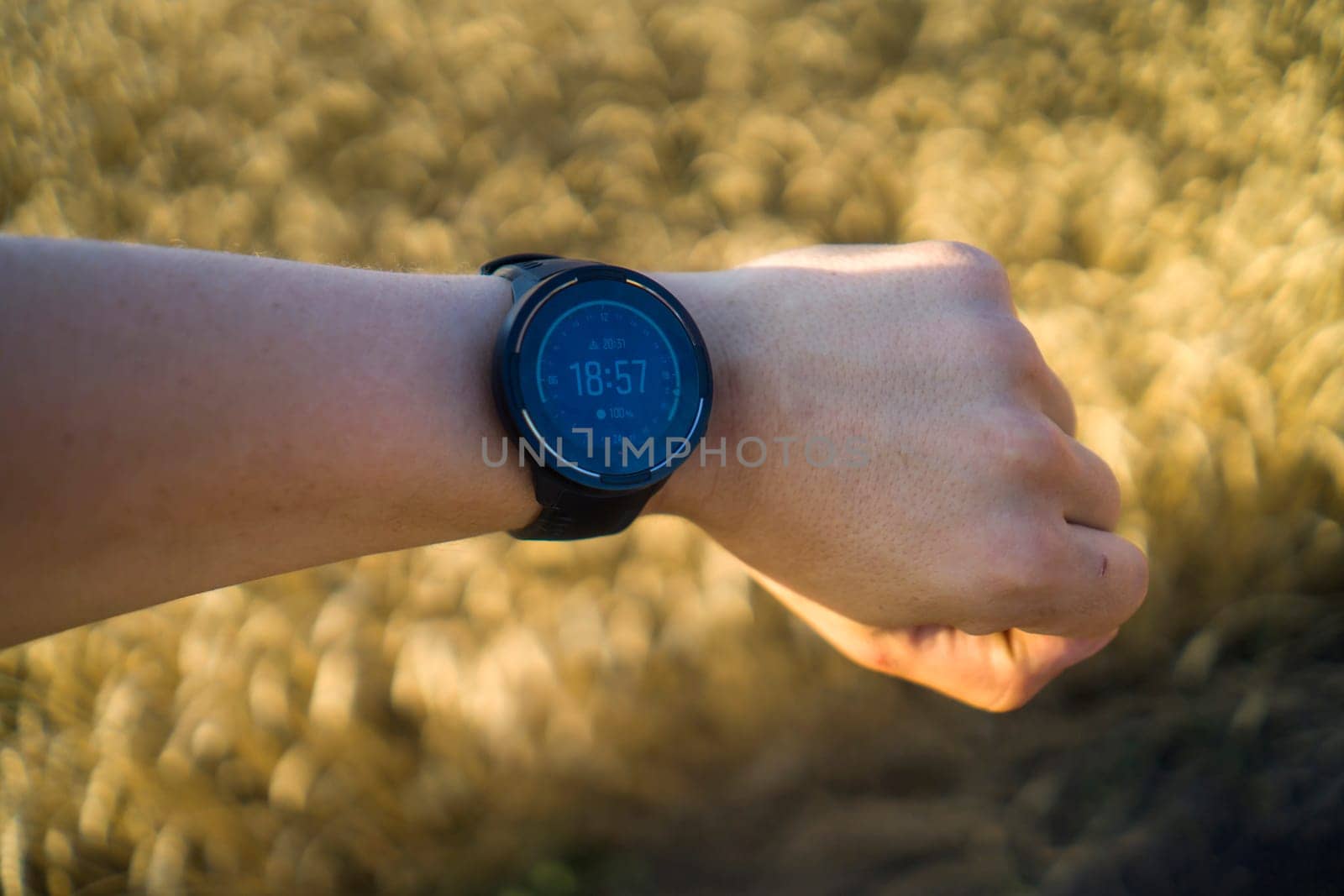 Men's hand with a smart waterproof functional watch showing running pace, heart rate monitor, barometer, built-in gps, heart rate monitor. A man is training outdoors with a modern device.