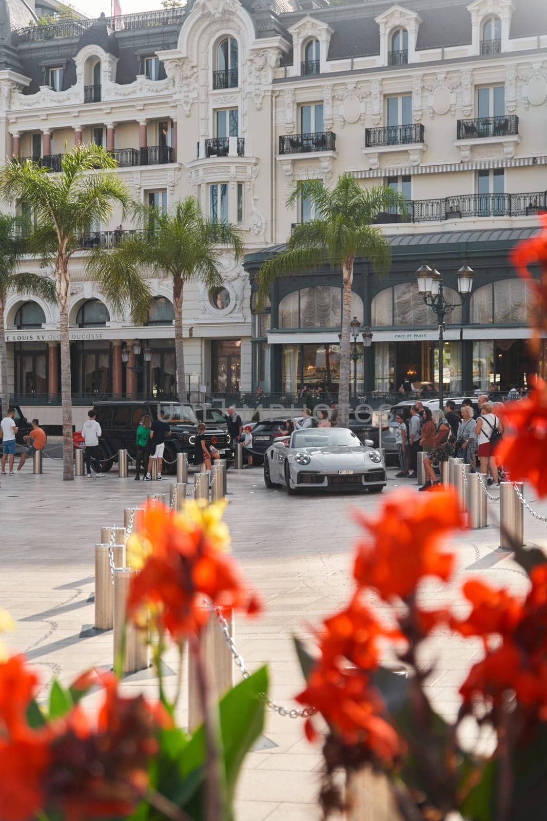 Monaco, Monte-Carlo, 22 October 2022: Square Casino Monte-Carlo at sunset, luxury cars, famous Hotel de Paris, wealth life, tourists take pictures of the landmark, pine trees, flowers. High quality photo