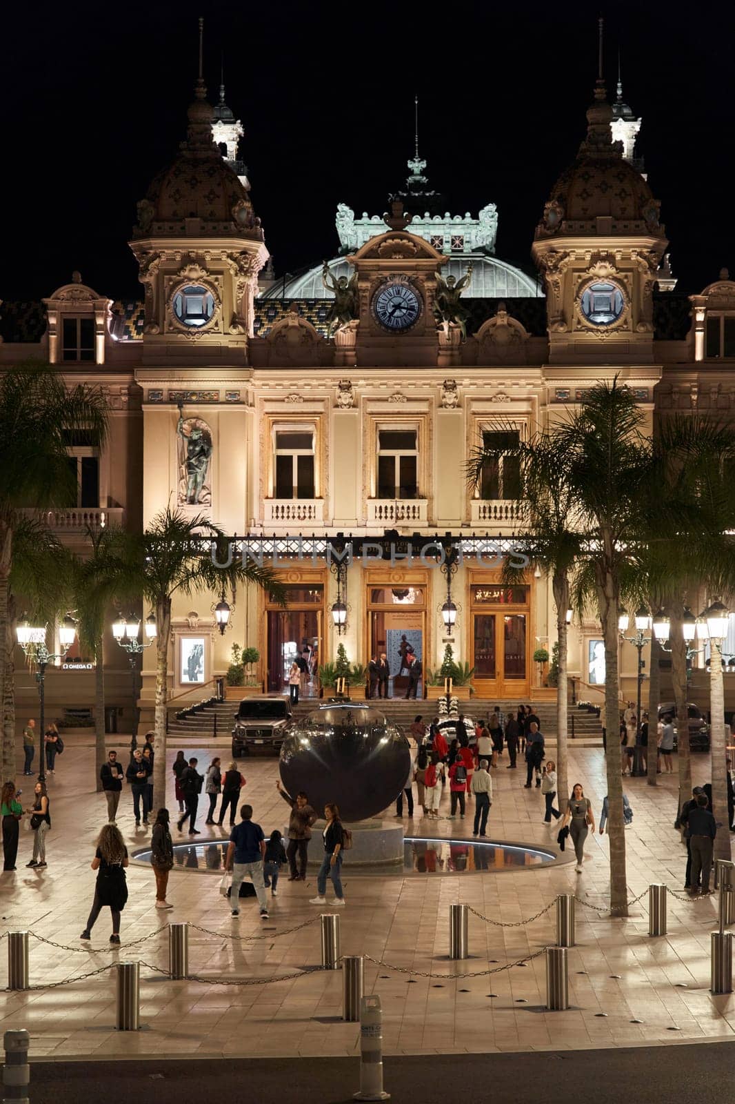 Monaco, Monte-Carlo, 12 November 2022: The famous square of Casino Monte-Carlo is at dusk, attraction night illumination, luxury cars, players, tourists, splashes of fountain. High quality photo