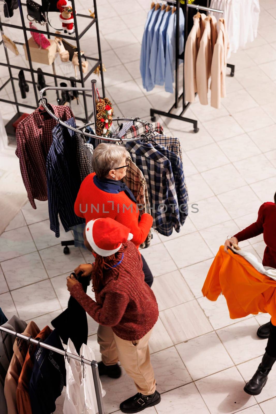 People making preparations for Christmas Eve activities and customs, customers looking for seasonal presents and festive attire. Shoppers at boutiques purchase goods in december.